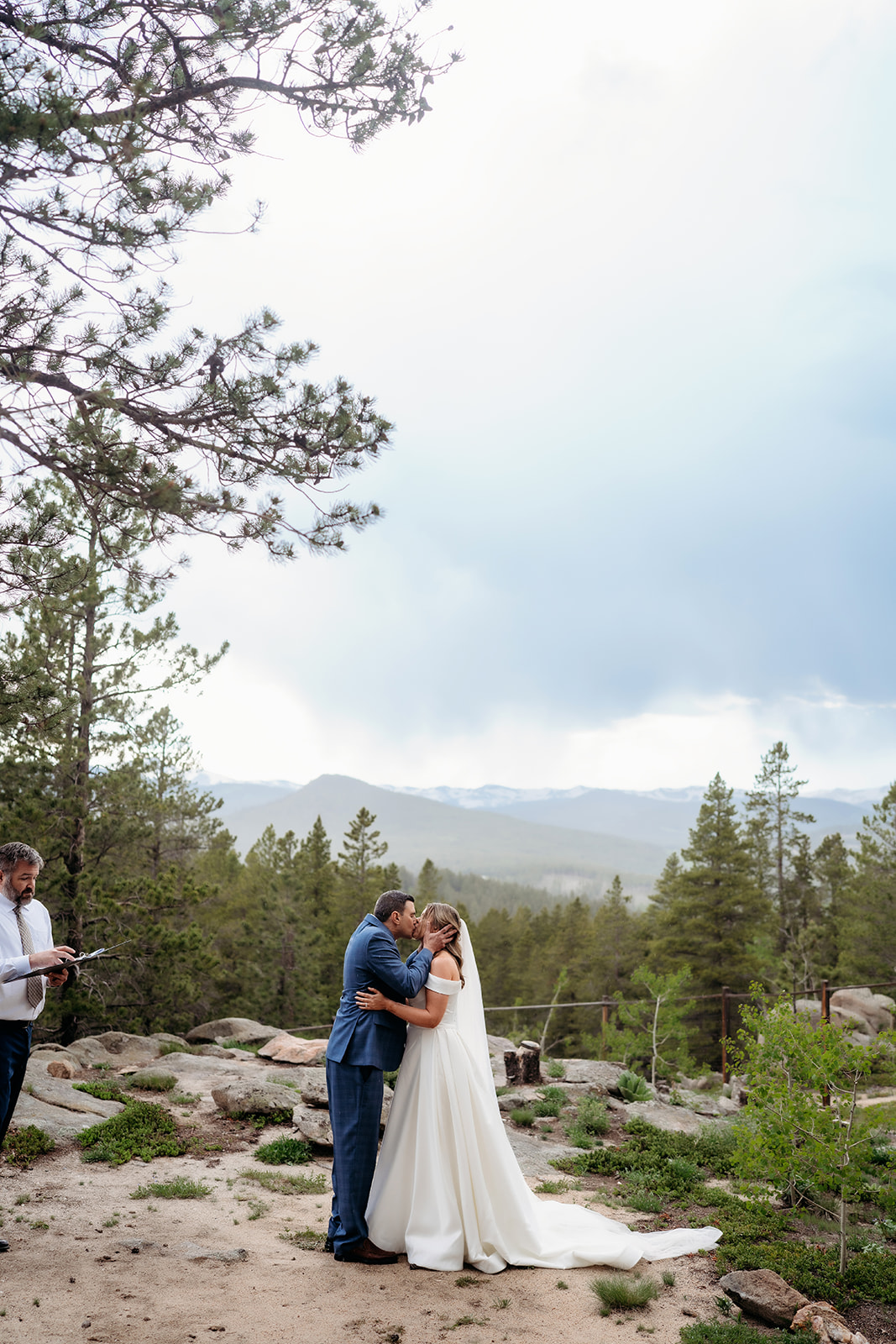 Bride and groom sharing a kiss beneath mountain skies during their Colorado adventure elopement ceremony.