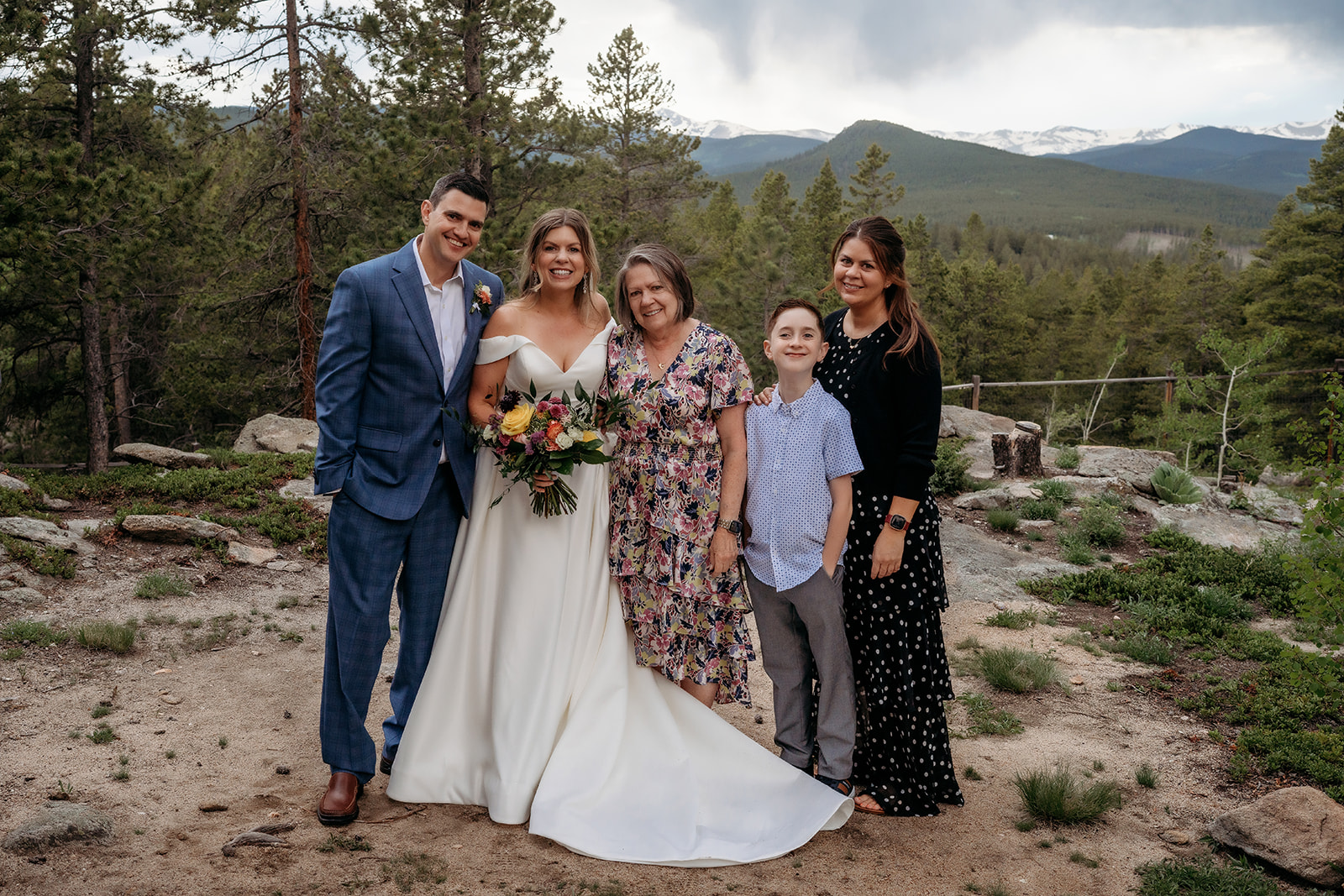 Bride and groom smiling with family members against mountain scenery at their Colorado adventure elopement.