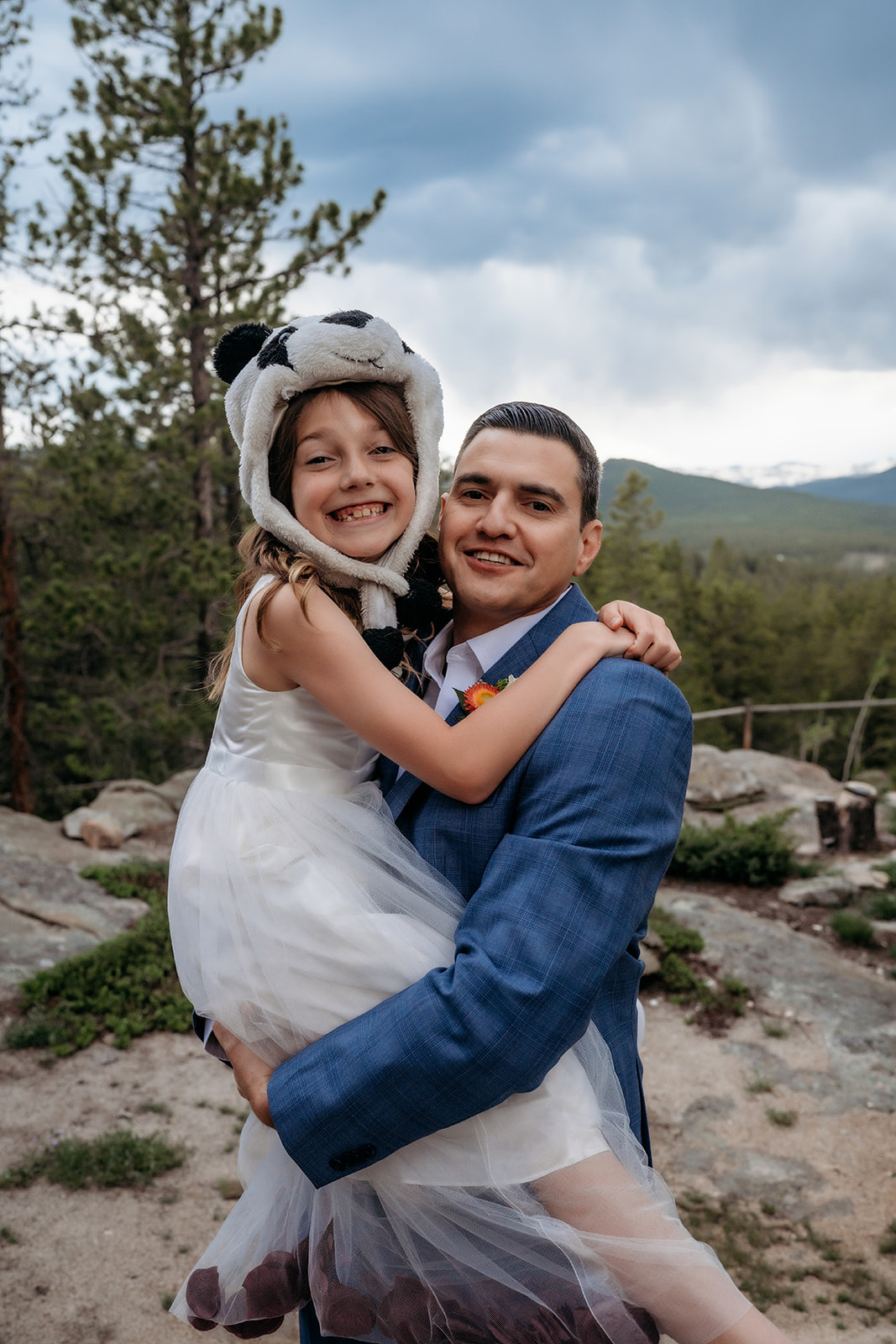 Groom holding young girl in a panda hat and white dress during their Colorado adventure elopement celebration.