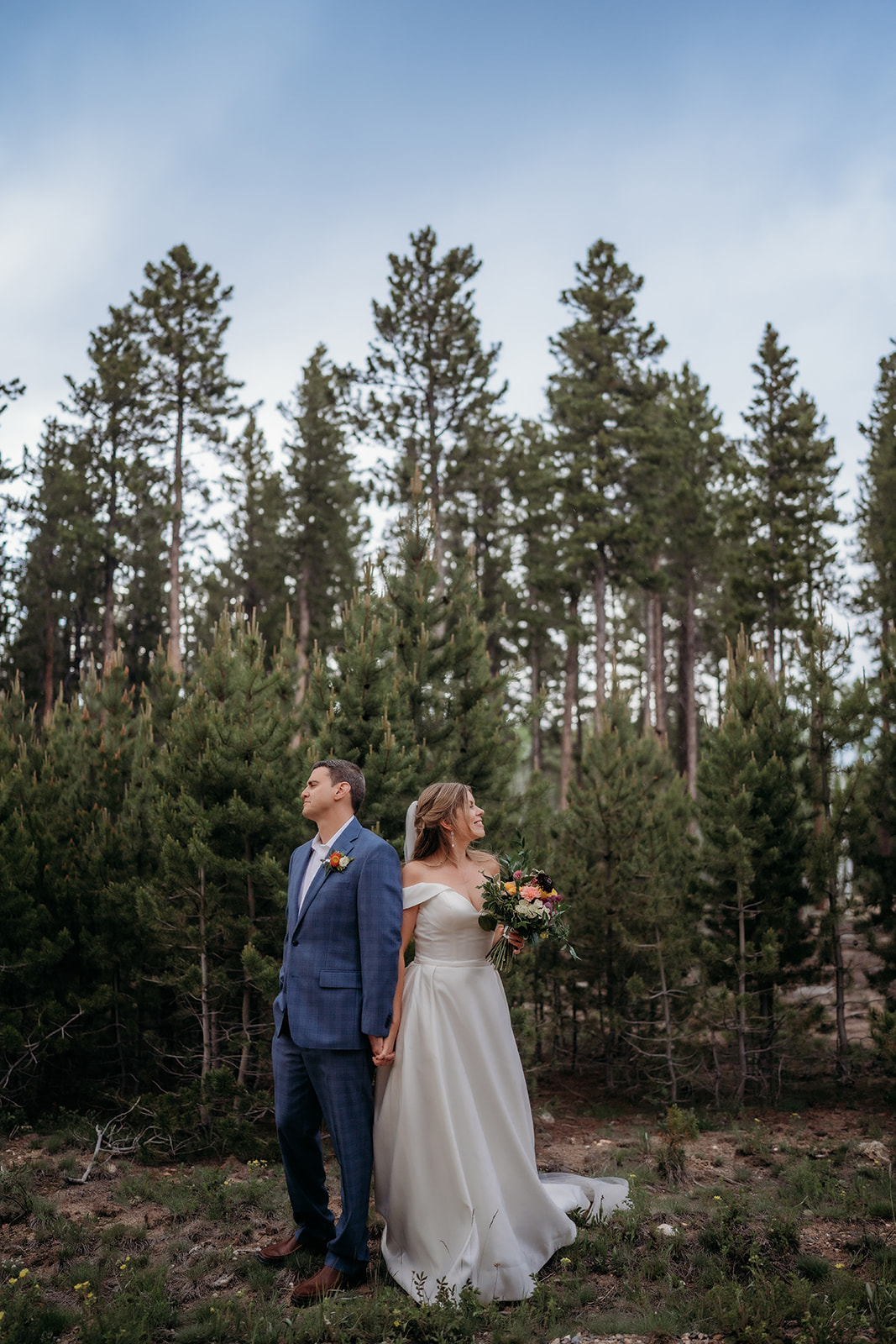 Bride and groom holding hands back to back after adventure elopement