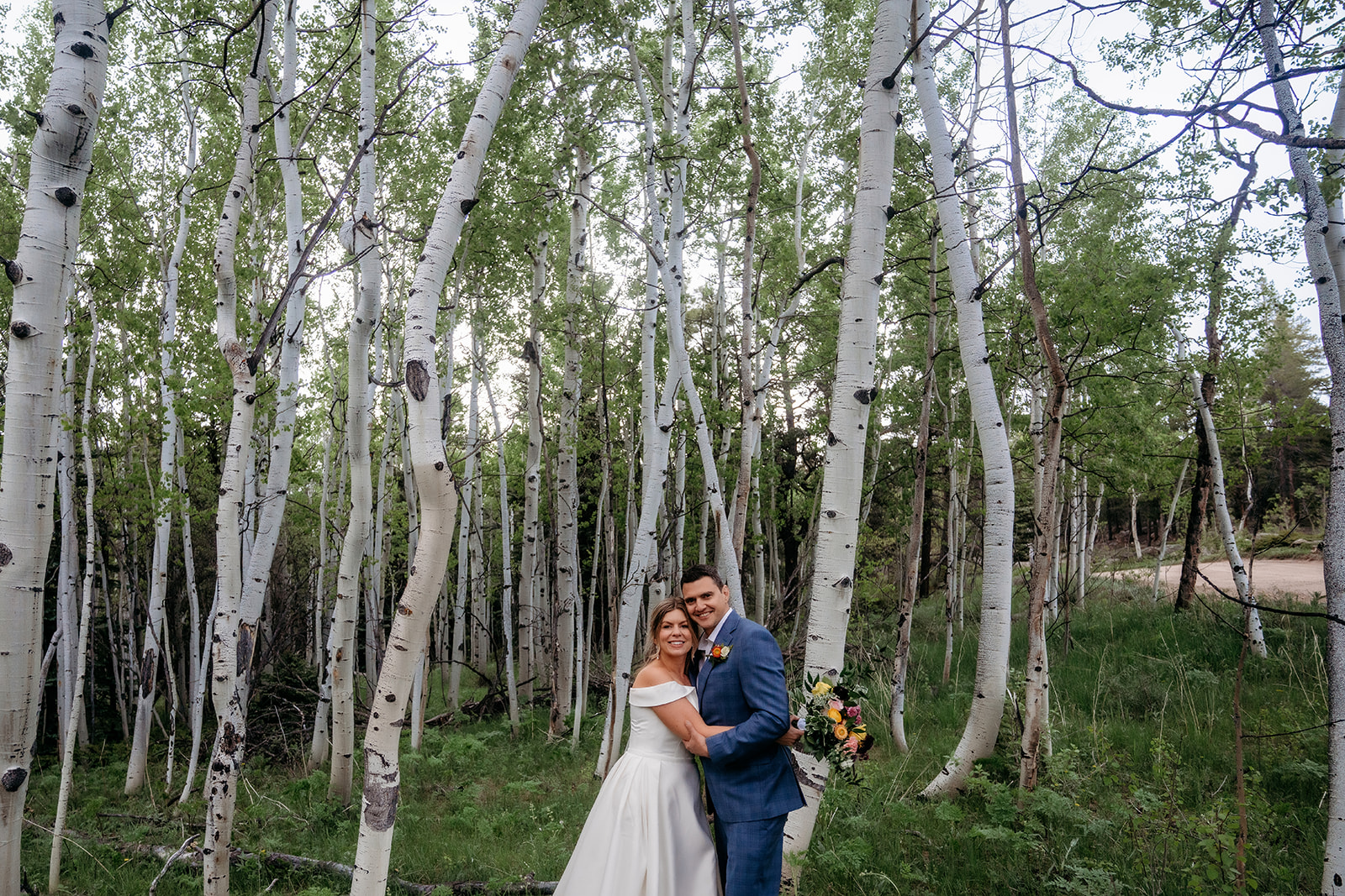 Bride and groom standing together in a grove of aspen trees during their Colorado adventure elopement.