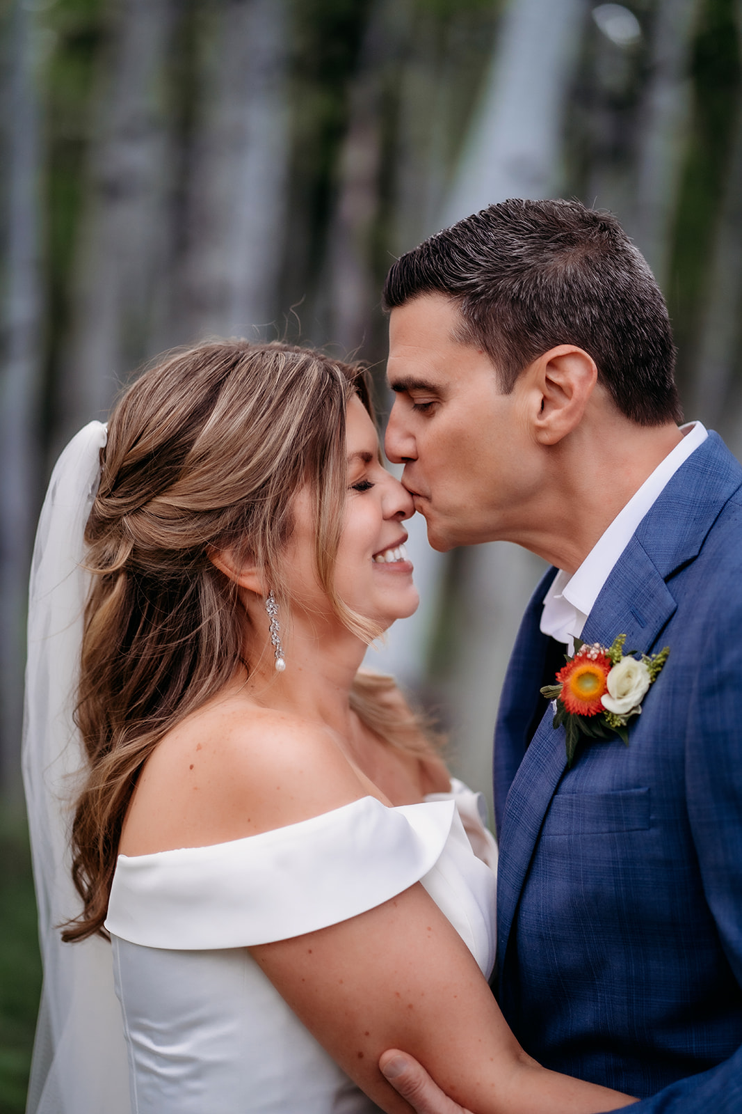 Groom kisses bride’s nose during a joyful moment in the forest on their Colorado adventure elopement.