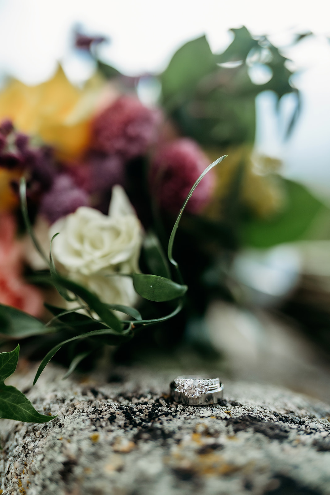 Wedding rings resting on a rock with bouquet in the background during a Colorado adventure elopement.