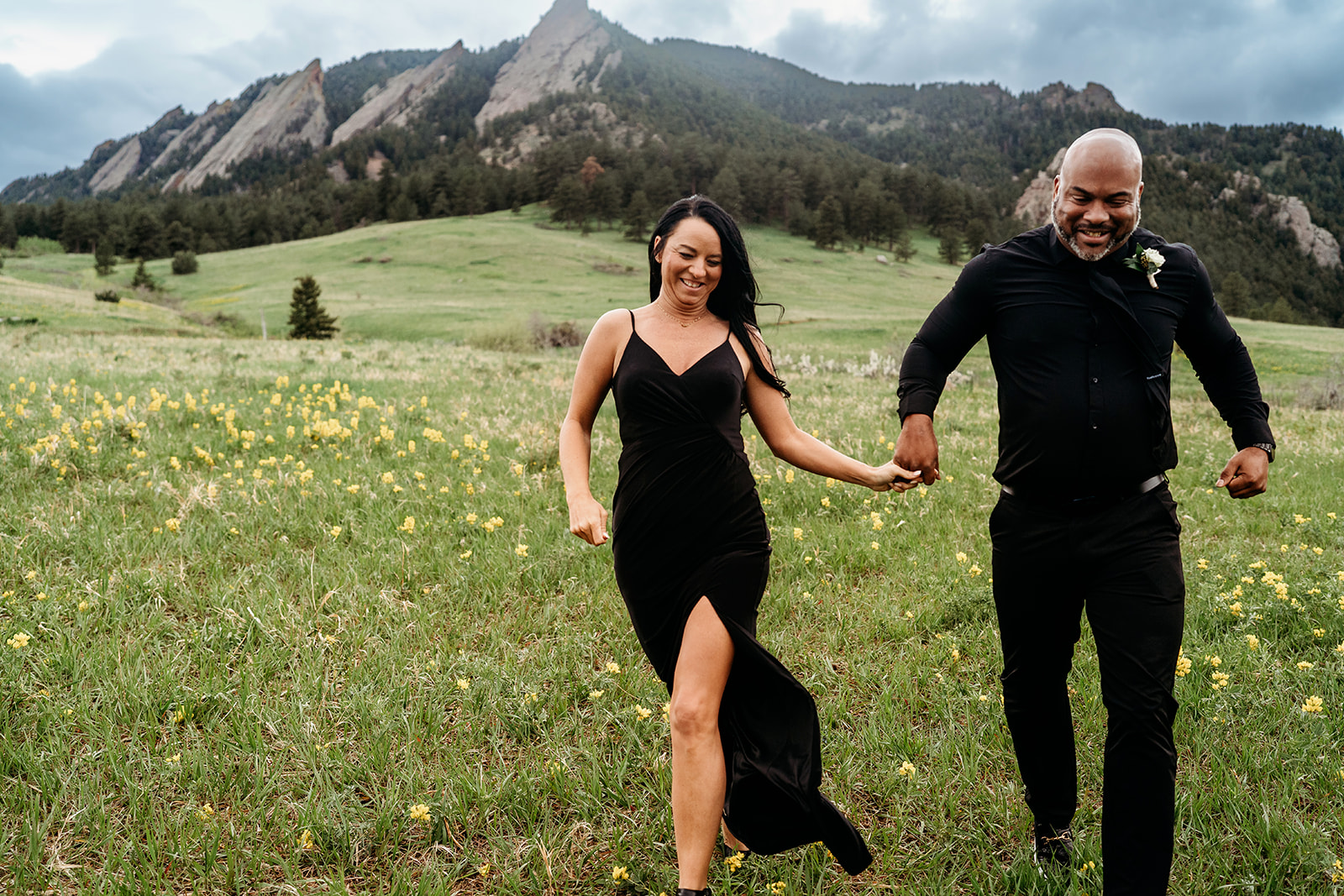 Smiling couple holding hands and running through a meadow of wildflowers on a summer day.
