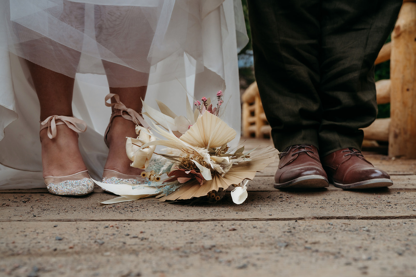 Close-up of the couple’s shoes and dried bouquet on a wooden dock, highlighting details from their intimate wedding day.
