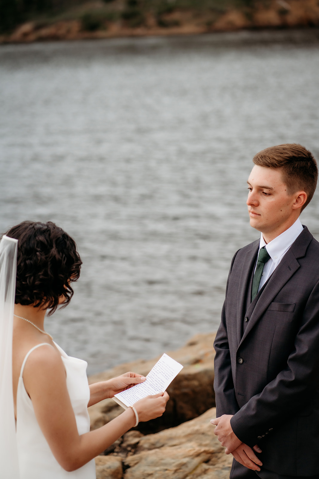 Bride reads vows to her groom during a heartfelt ceremony at one of the serene Colorado elopement locations by the water.