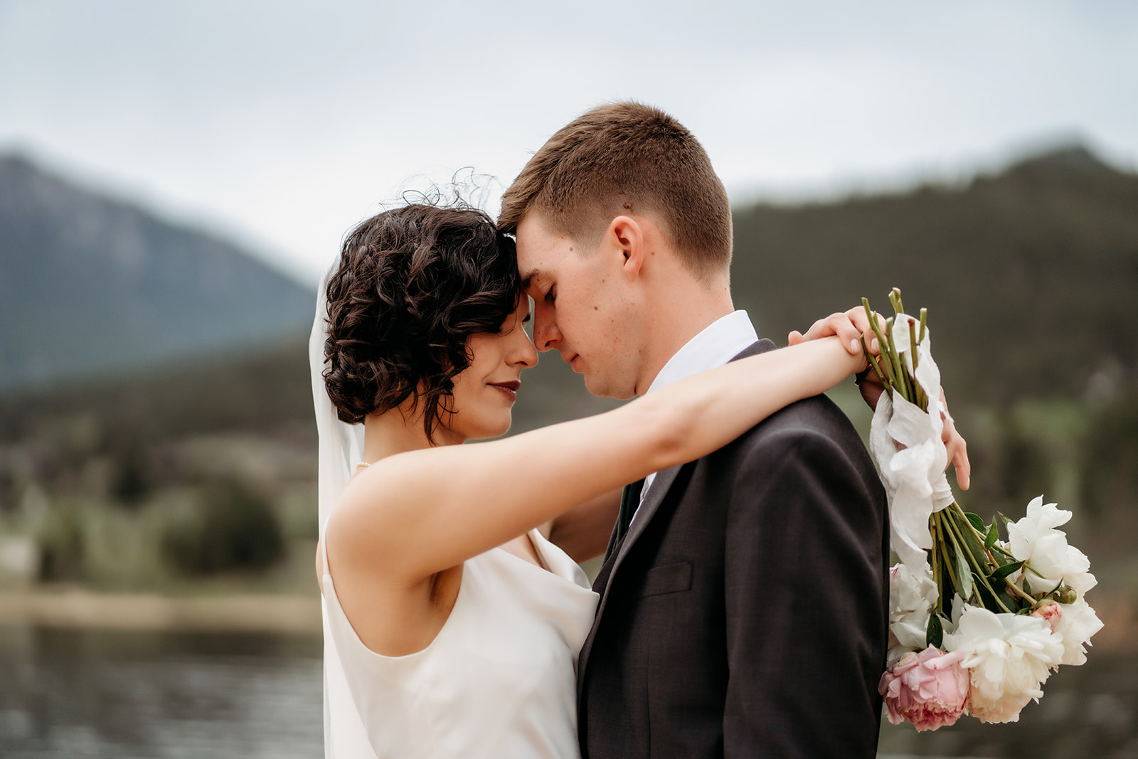 Bride and groom share an emotional forehead touch beside the lake at one of the most romantic Colorado elopement locations.