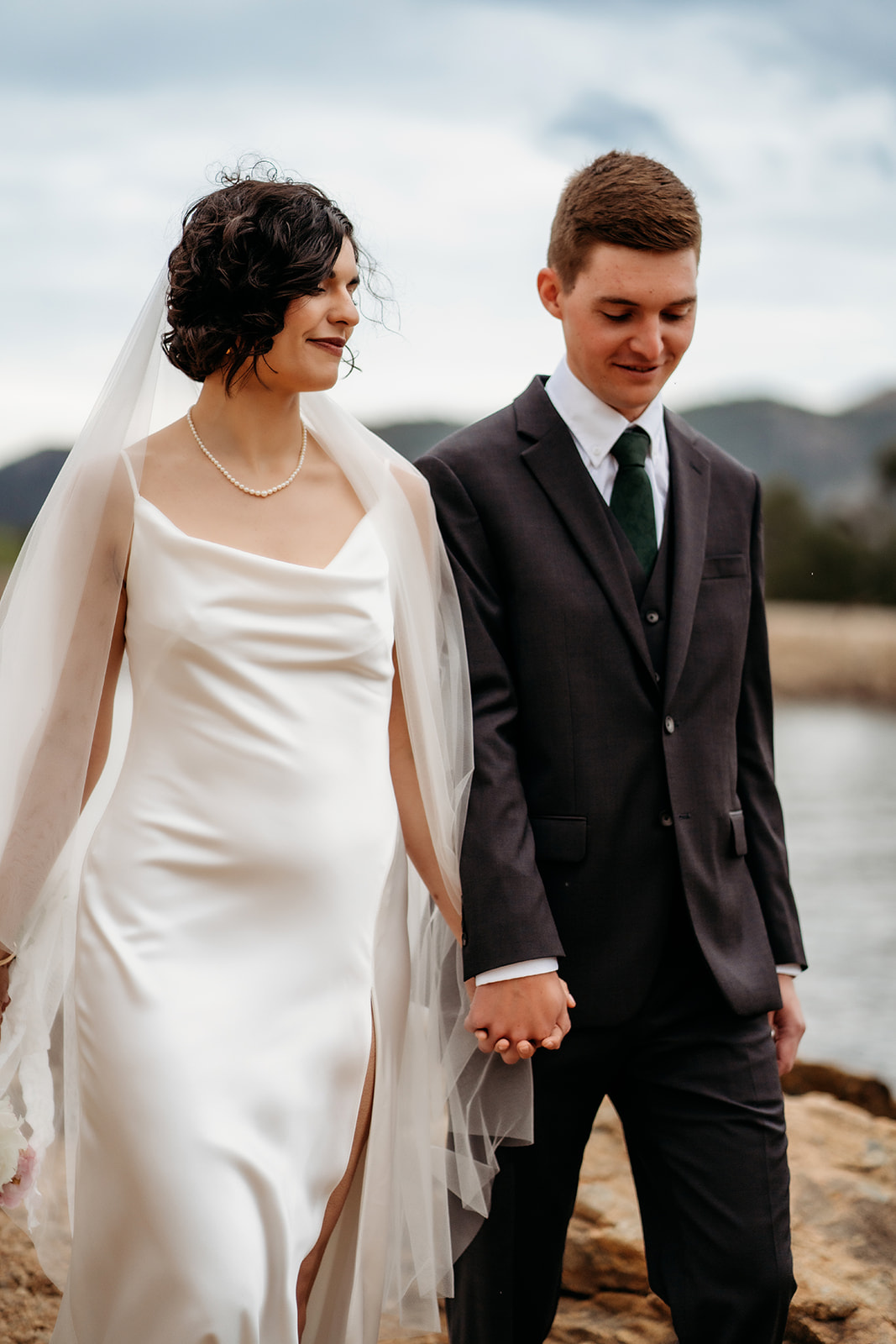 Newlyweds walk hand in hand along the shoreline, enjoying a quiet moment together after their vows.