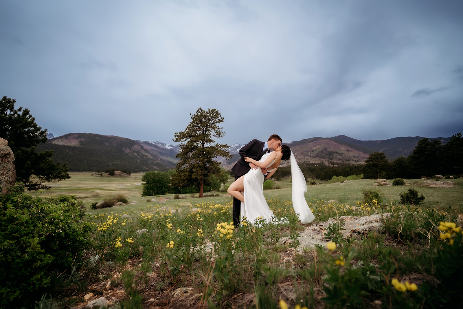 Groom dips the bride for a romantic kiss in a field of yellow wildflowers, one of the most picturesque Colorado elopement locations.