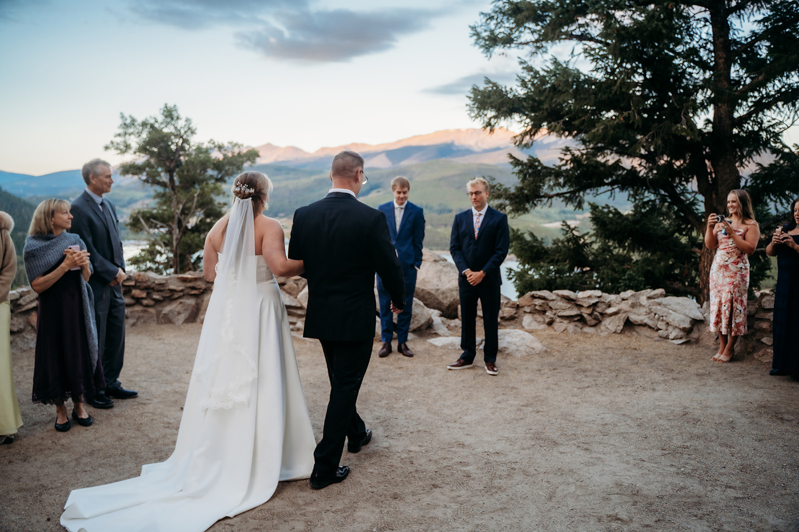 Bride walking down the aisle with her father toward the groom, outdoor mountain wedding setting, by Denver elopement photographer.
