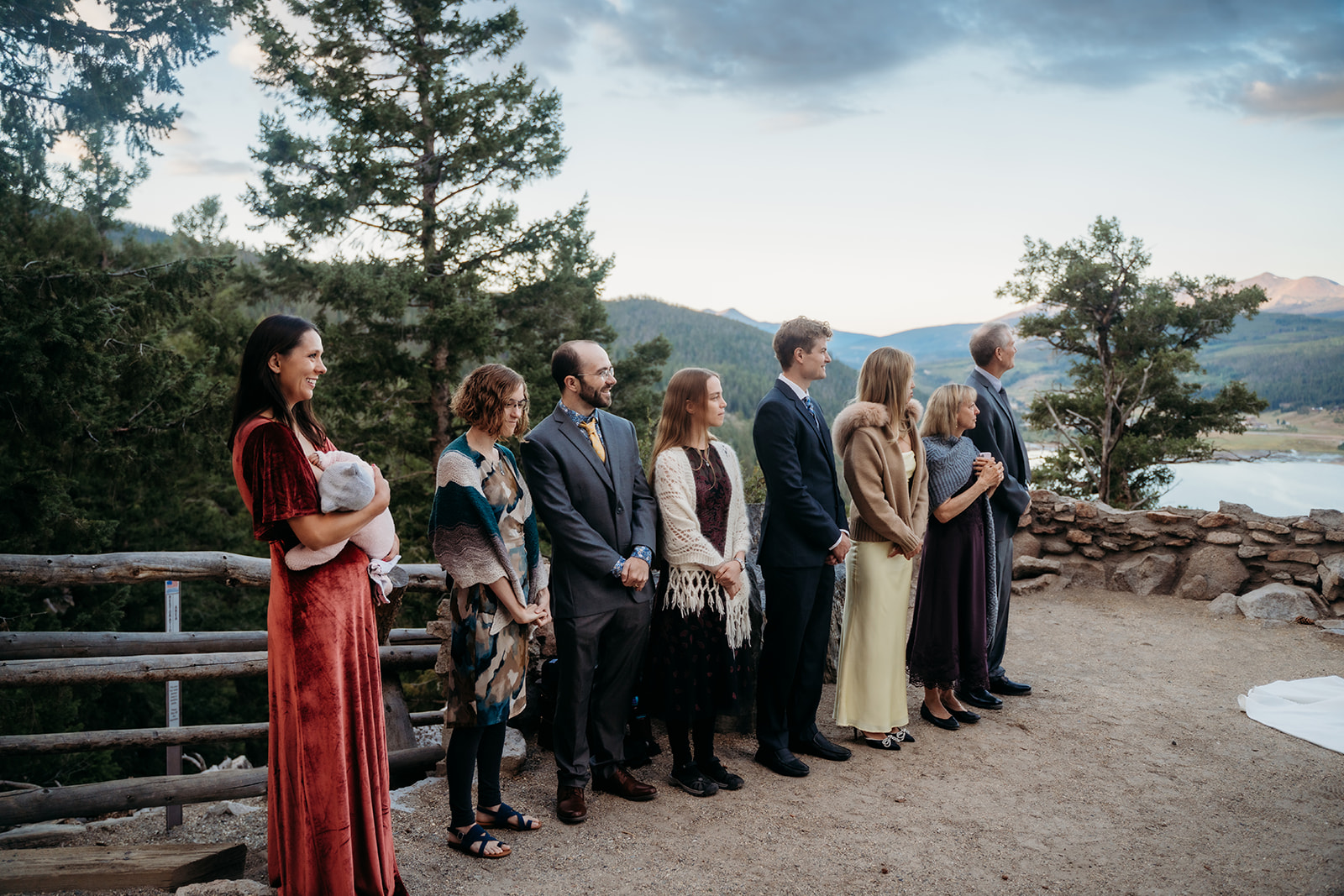 Family and friends standing in a line, smiling as they watch the couple’s mountain wedding ceremony.