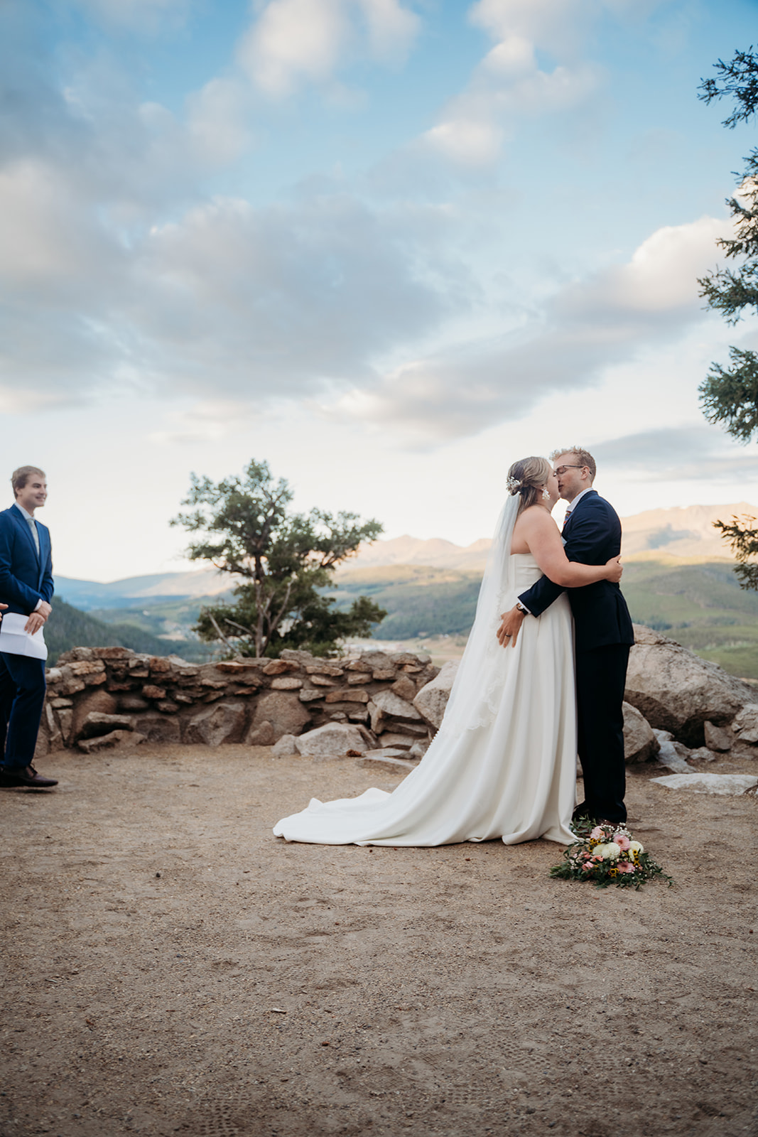 Bride and groom sharing their first kiss as a married couple during intimate mountain ceremony.