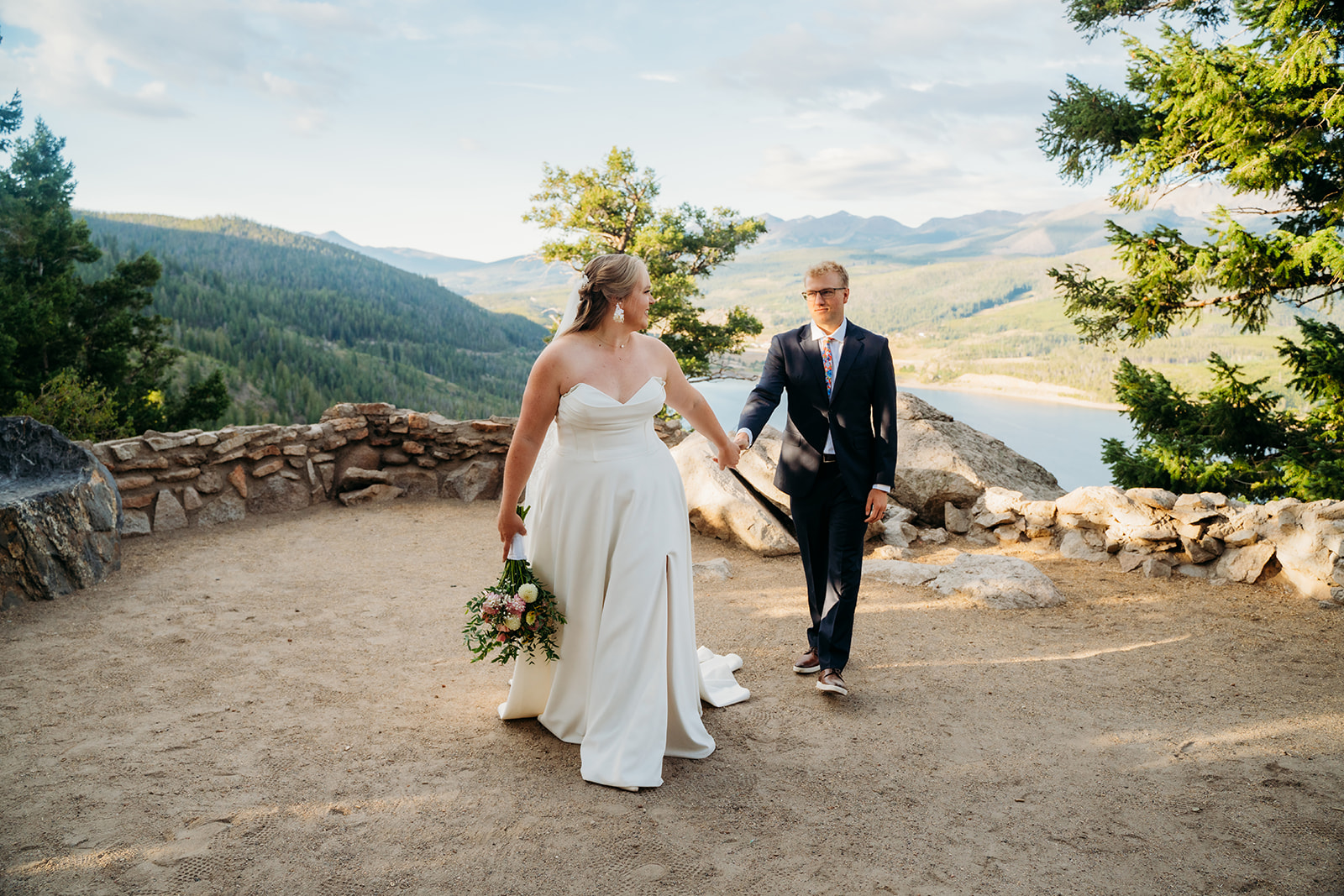 Bride holding bouquet while walking hand in hand with groom during their intimate outdoor wedding, by Denver elopement photographer.