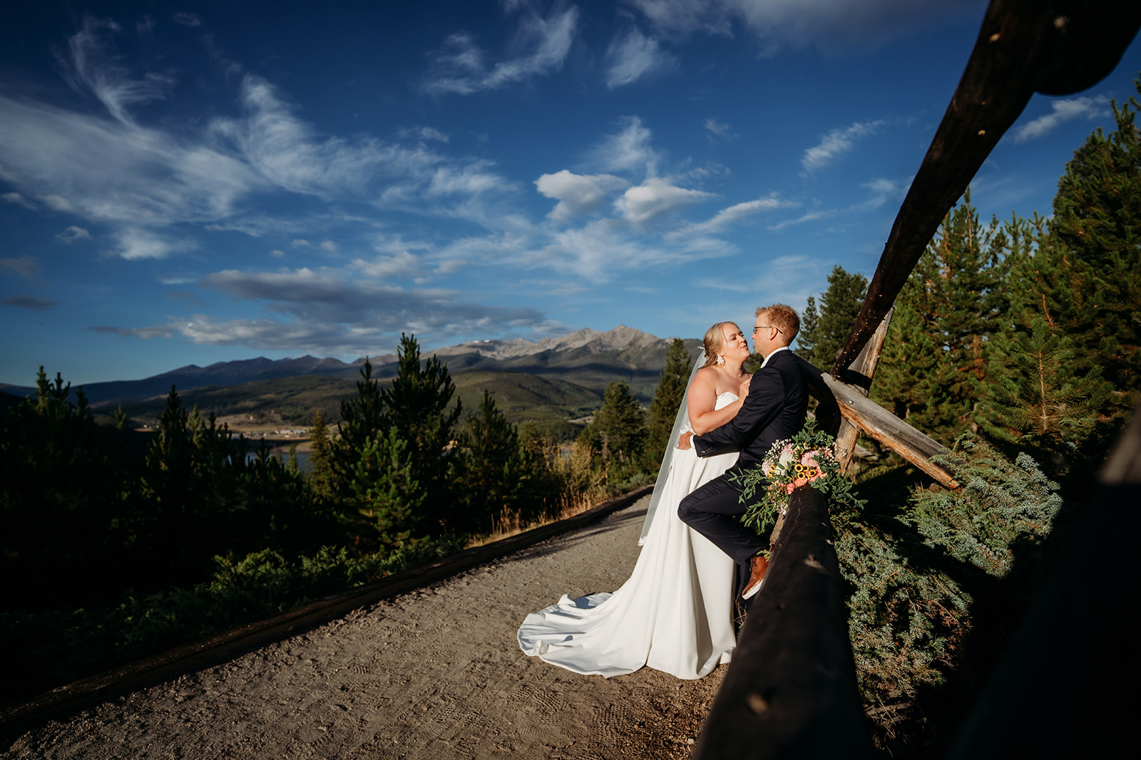 Bride and groom walking hand in hand into the sunset, veil and bouquet glowing in golden light, photographed by a Denver elopement photographer.
