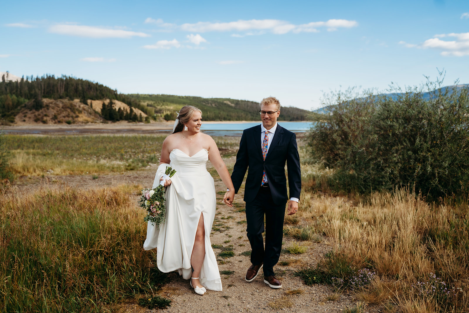 Bride and groom walking together through meadow by Denver elopement photographer