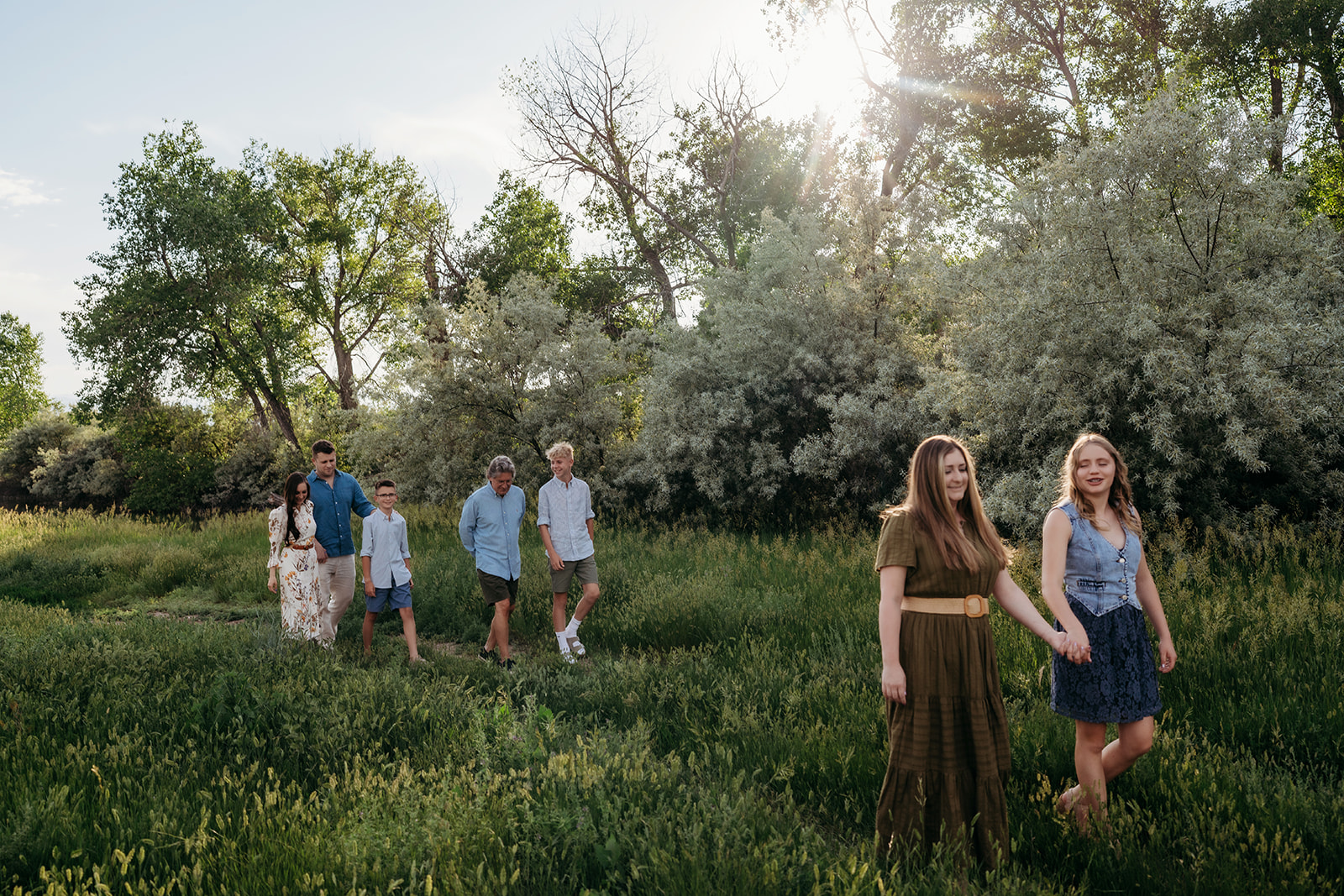 Group walking through tall grass at golden hour, wearing breezy and comfortable outfits.