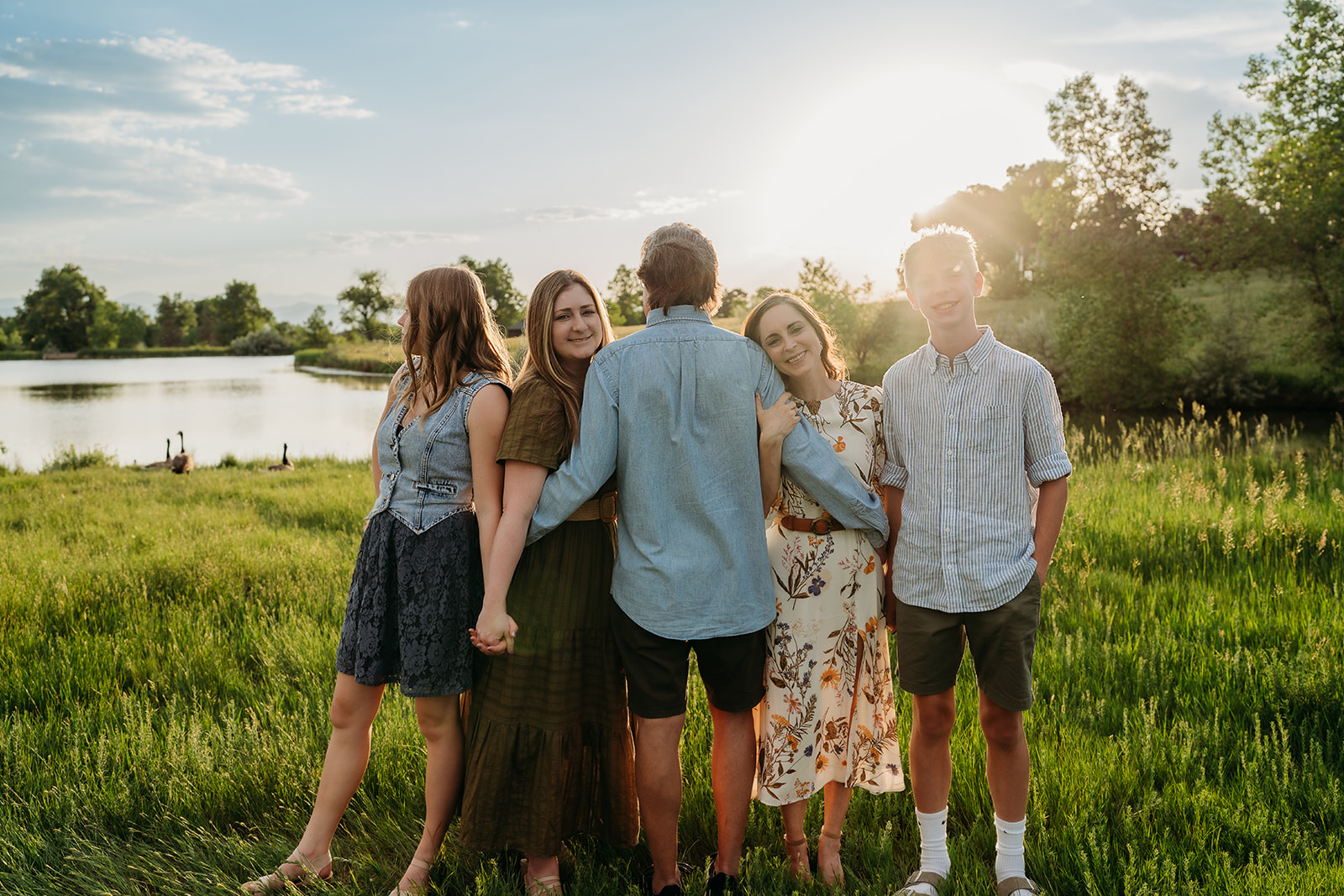 Group of siblings standing arm in arm at sunset, dressed in neutral tones perfect for family photos.