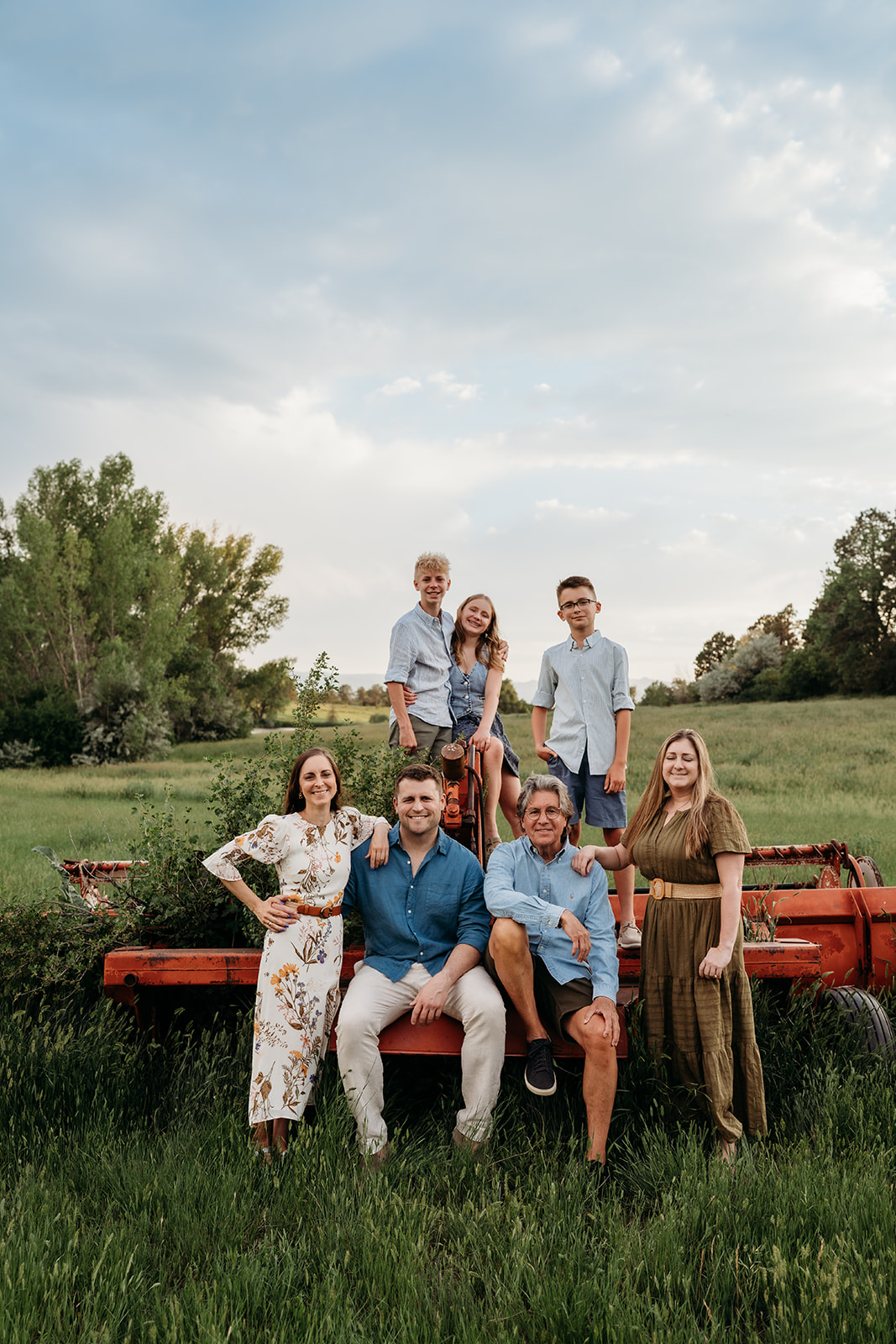 Large family standing in a green meadow, blending casual and dressy outfits for family portraits.
