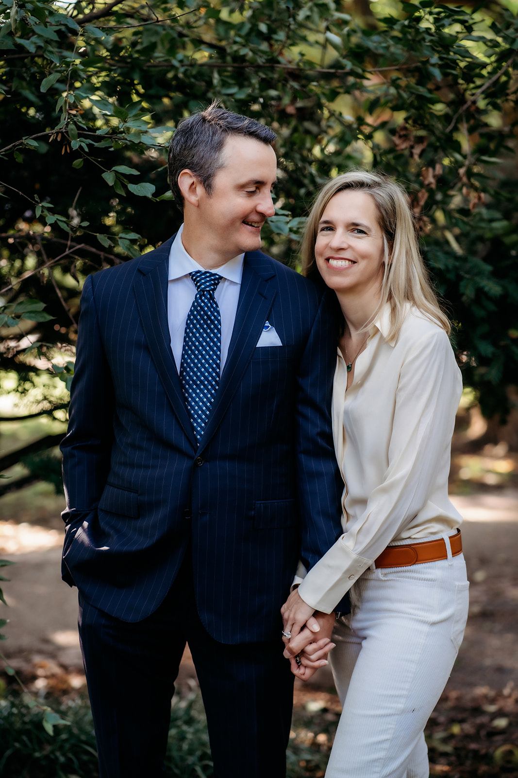 Husband looks over at wife smiling while holding her hand during annual family photos