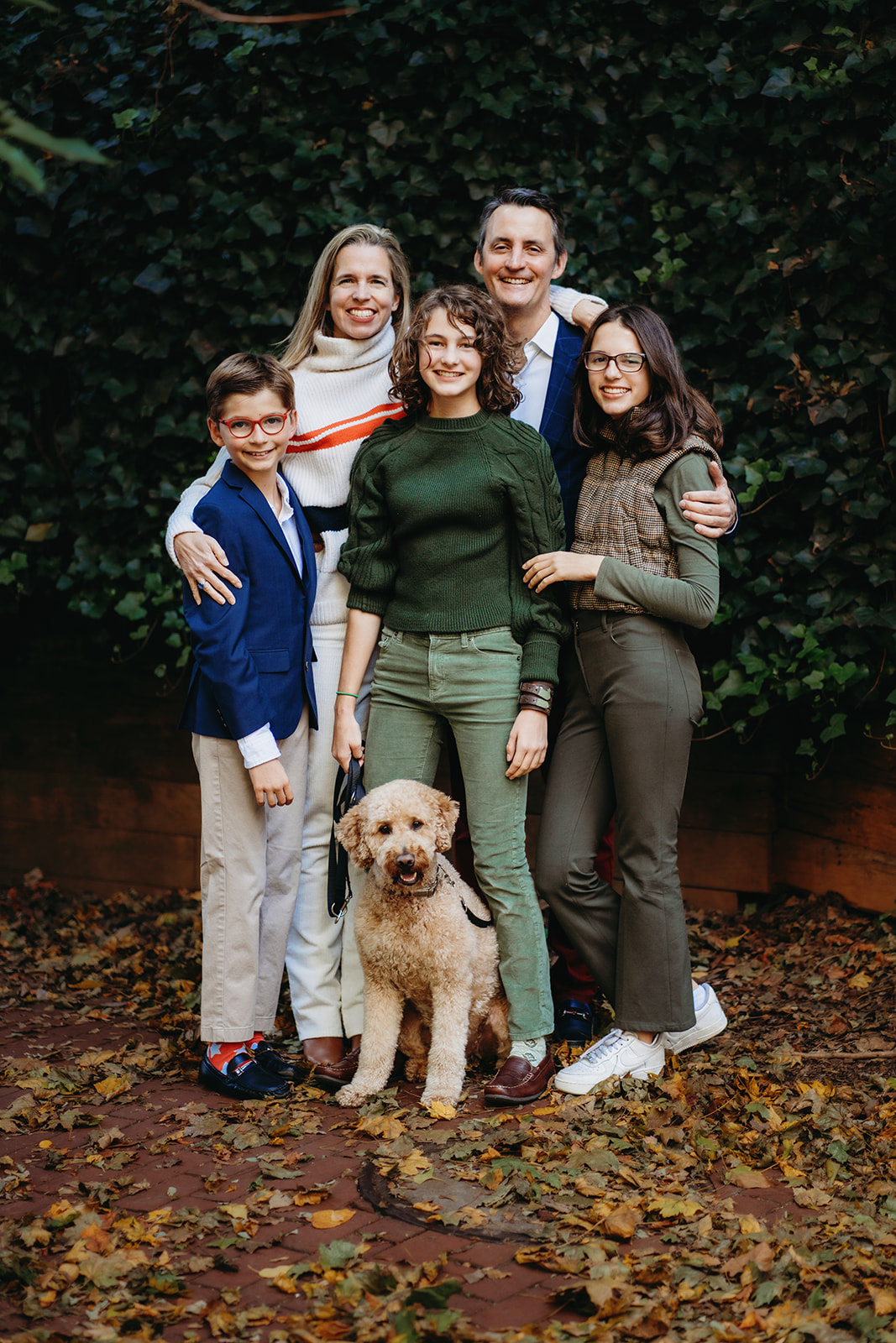 Family embraces one another during annual family photos with dog standing in front