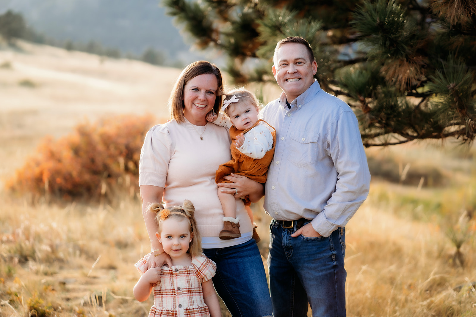 Mother and father smiling at their baby while their older daughter stands close during family photos Denver.