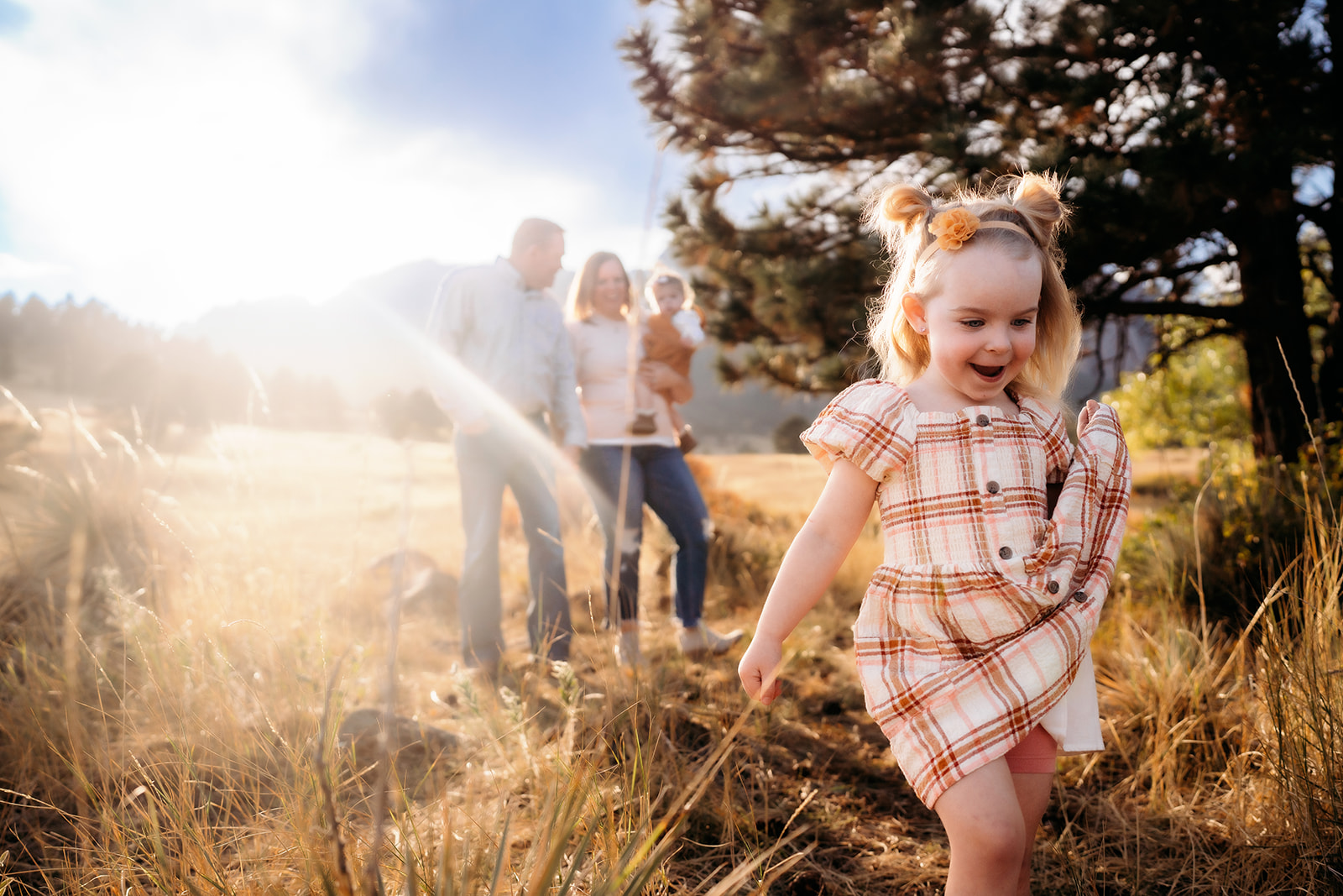 Little girl running joyfully in the foreground while her family smiles in the background during family photos Denver.