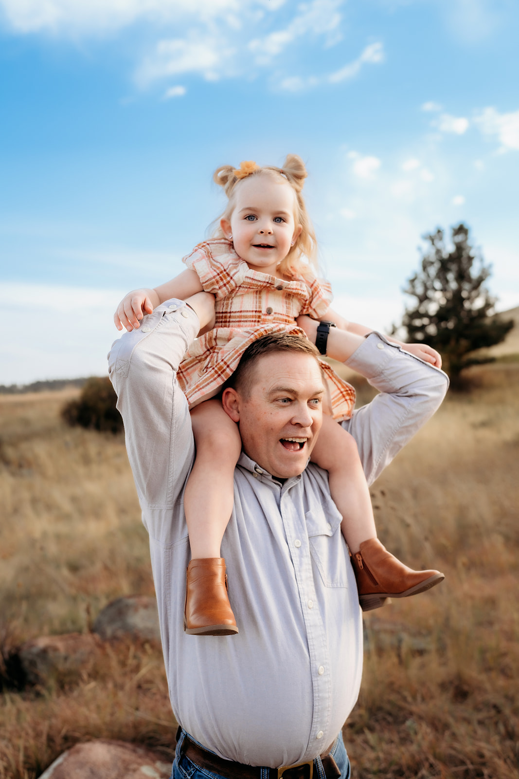 Father carrying his daughter on his shoulders, both smiling during family photos Denver in the mountains.