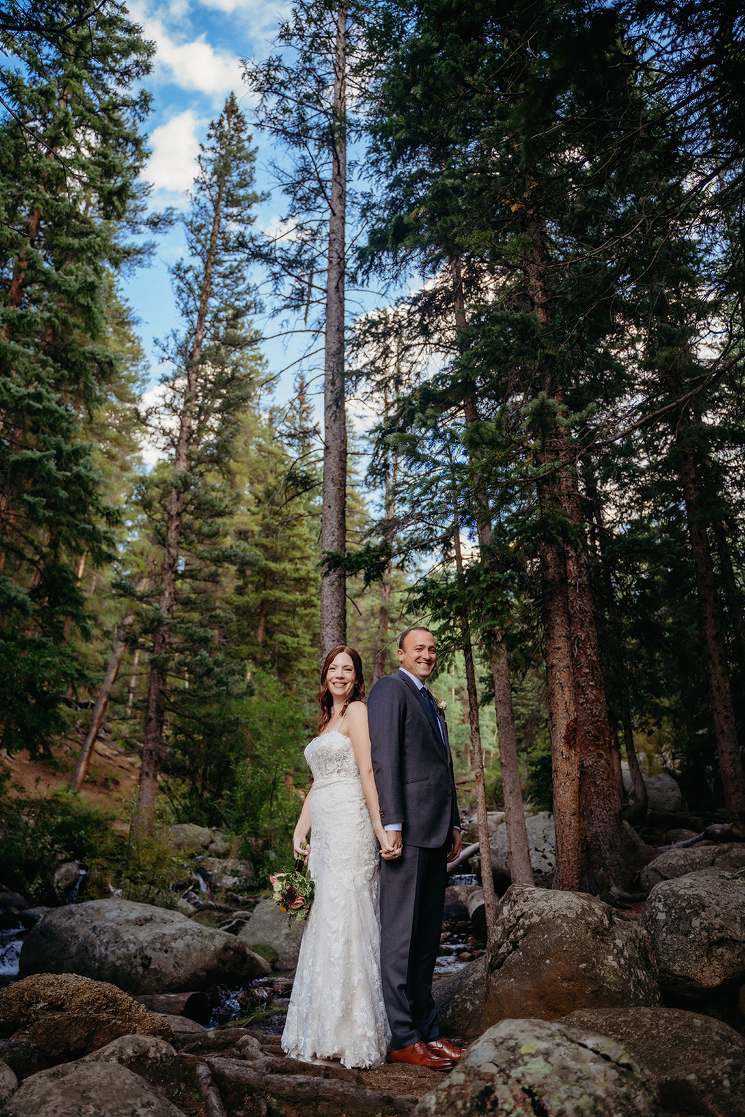Back to back with hands linked, this couple celebrates their elopement in Colorado in the heart of the woods.