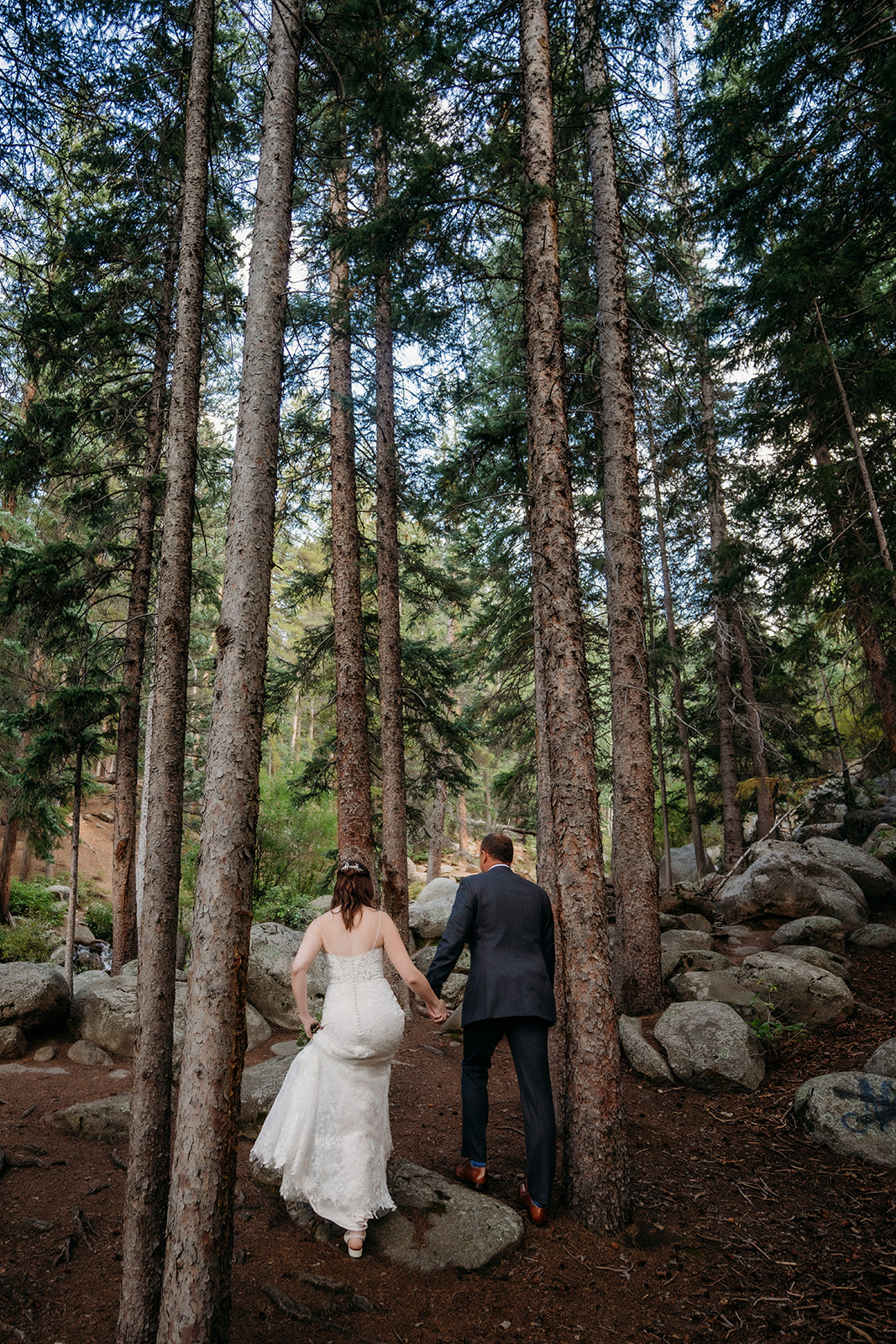 The bride and groom walk side by side beneath a bright sky, beaming after saying their vows.
