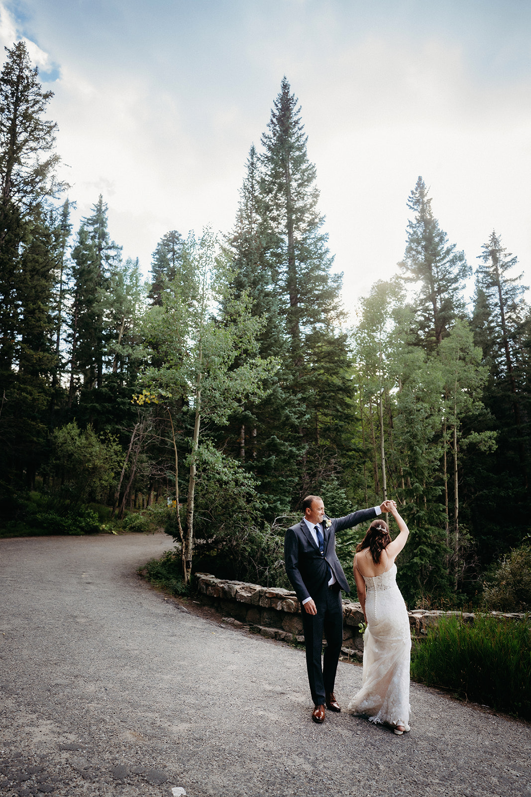 Mid-twirl, the groom spins his bride under the trees as the sun begins to set.