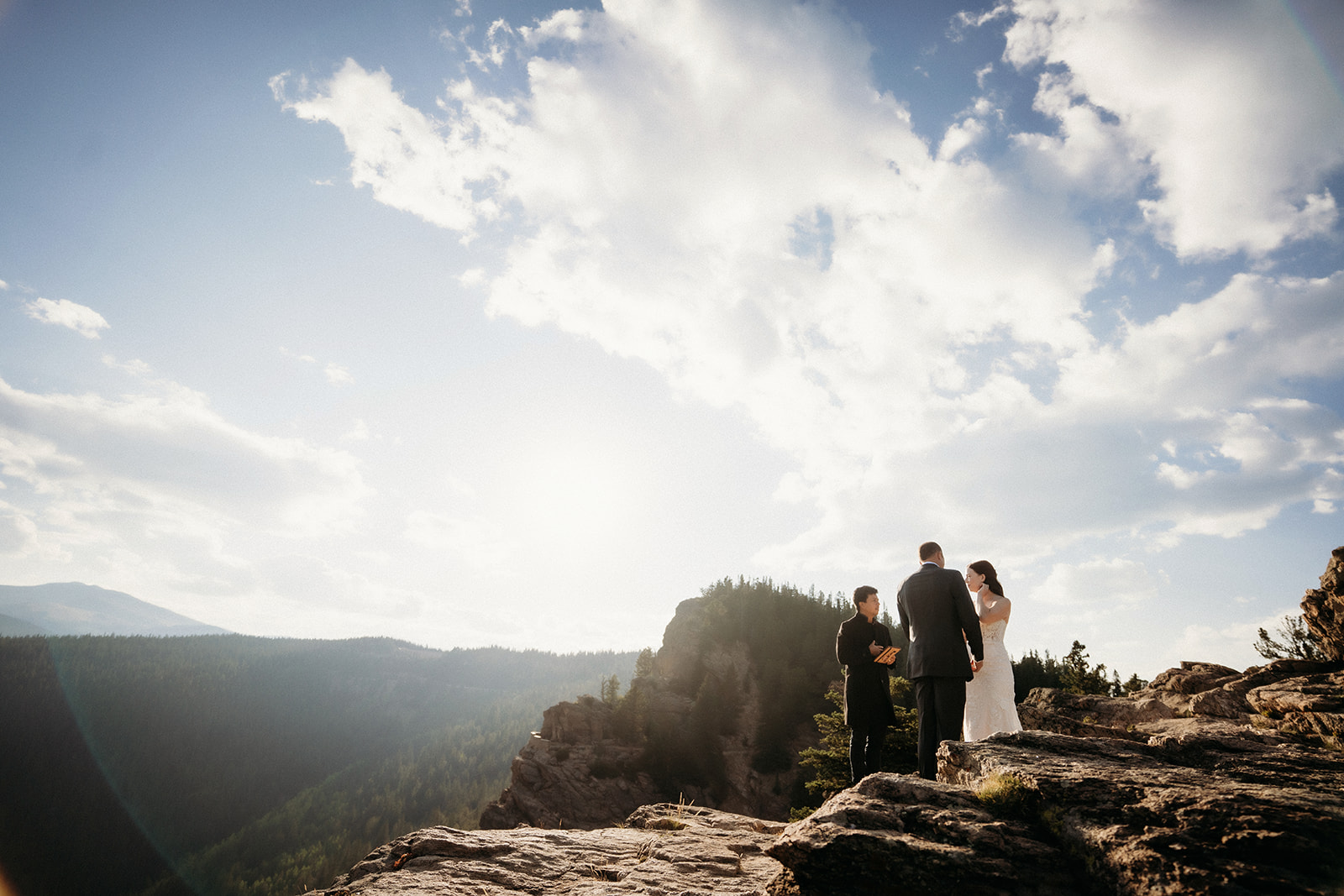 With light pouring through the clouds, this couple exchanges vows on a rocky overlook during their elopement in Colorado.
