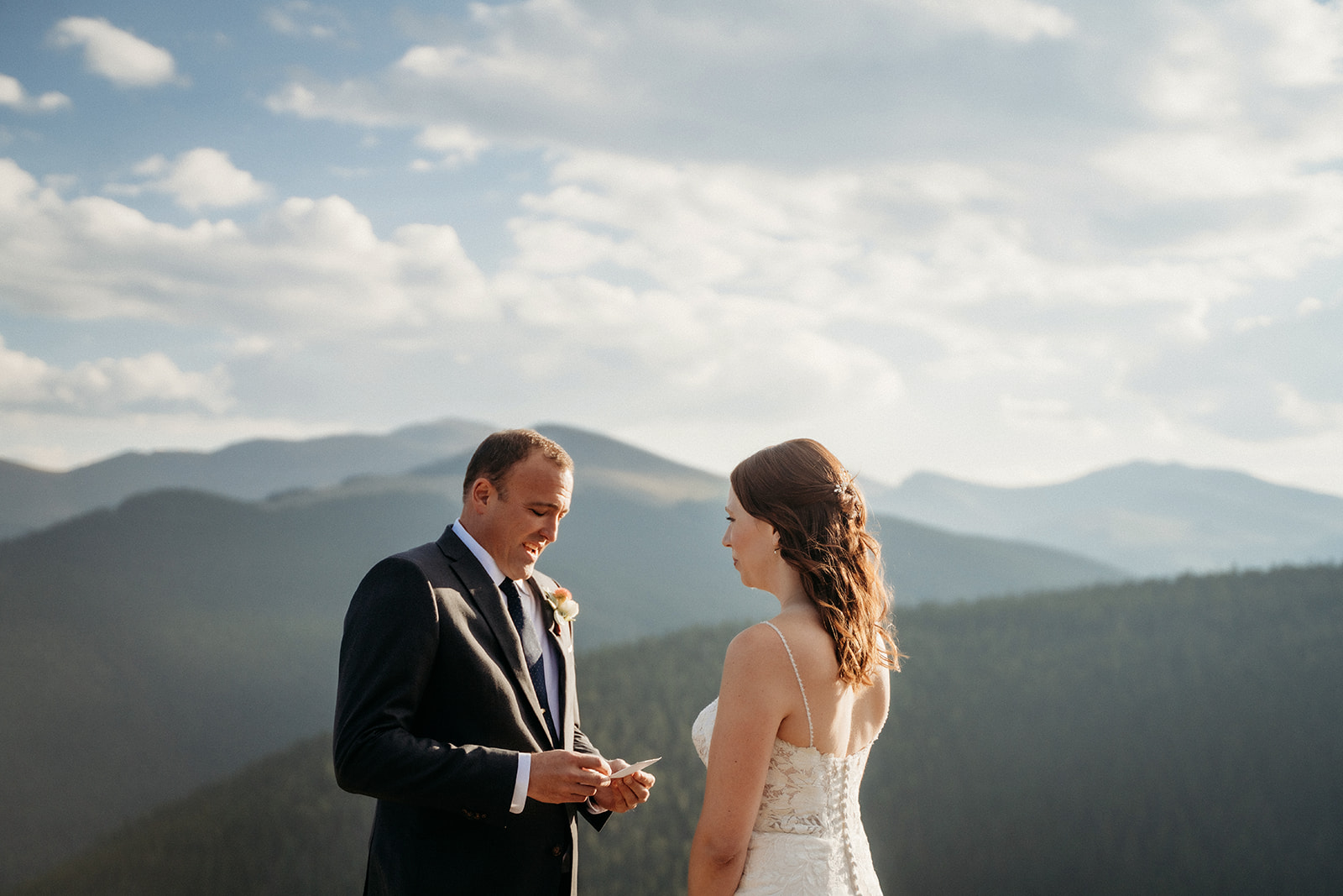 The groom reads his vows with a backdrop of layered mountains behind him, his voice full of emotion.