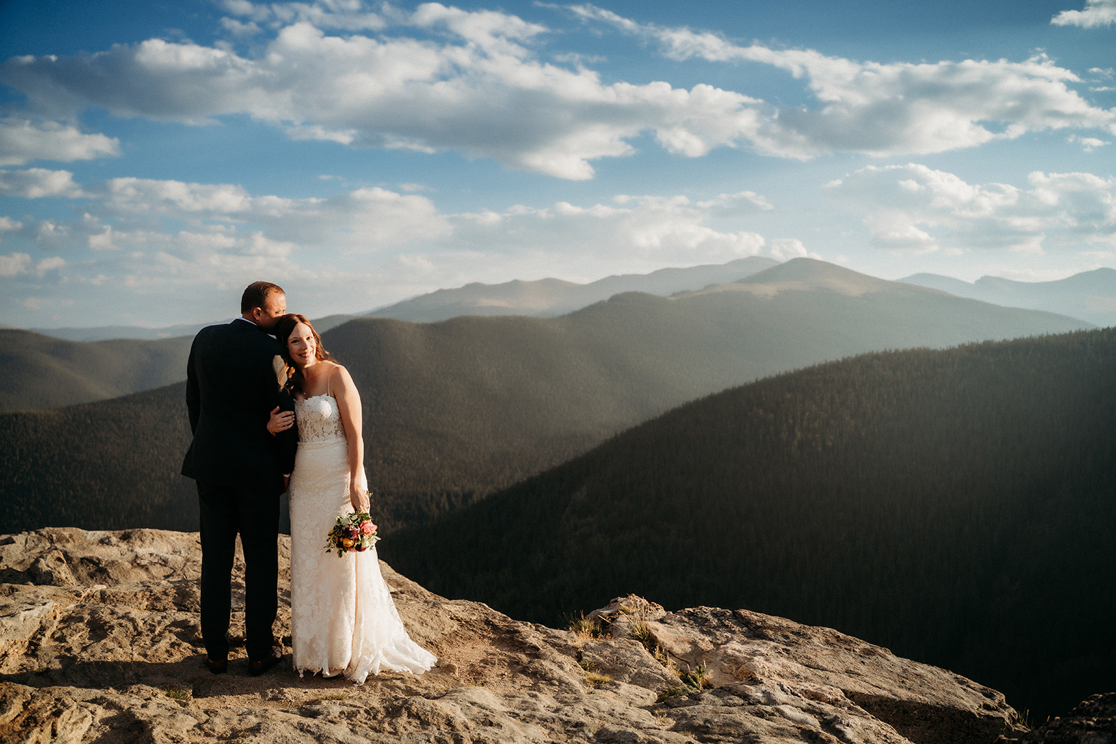Embracing at the edge of a cliff, this couple shares a peaceful moment during their breathtaking elopement in Colorado.