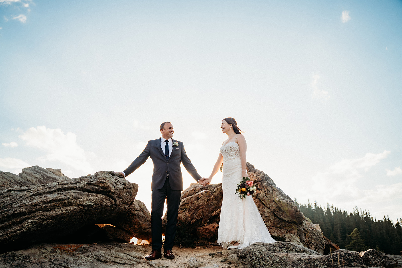 Standing hand in hand atop dramatic boulders, the couple embraces adventure and love during their elopement in Colorado.