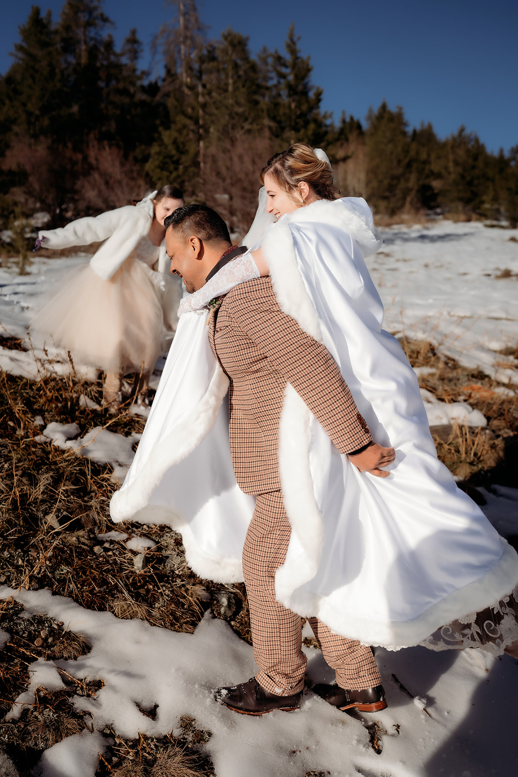 Couple and their daughter walk hand-in-hand through patches of snow and golden grass, laughing in the crisp mountain air.