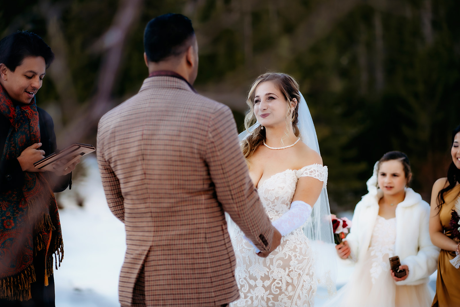 Bride looks lovingly at the groom while holding hands during their heartfelt winter elopement ceremony in Colorado.