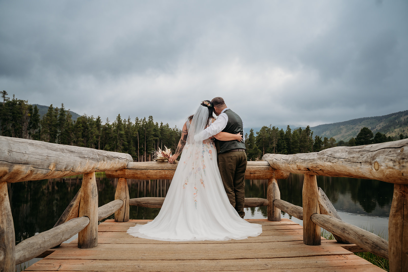 Bride and groom embrace while gazing at the lake together, soaking in the peaceful beauty of their intimate wedding day.