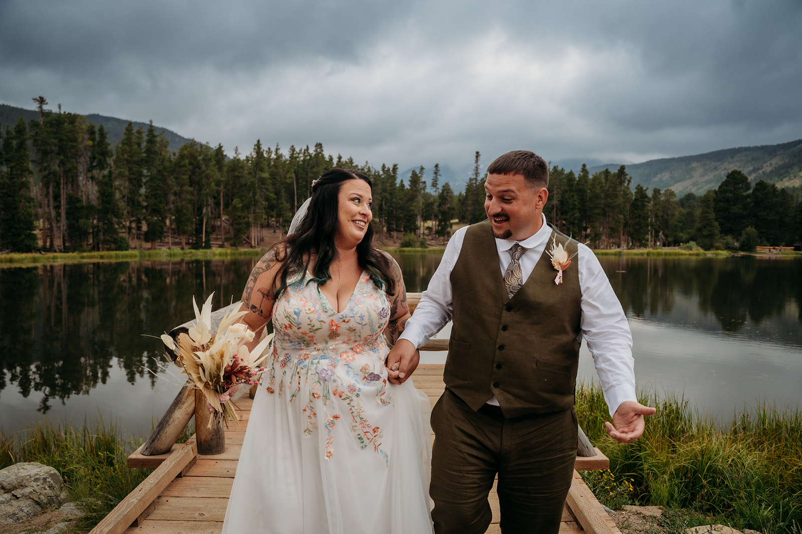 Bride and groom walk hand-in-hand across the dock, smiling at each other with laughter and love after their intimate wedding ceremony.