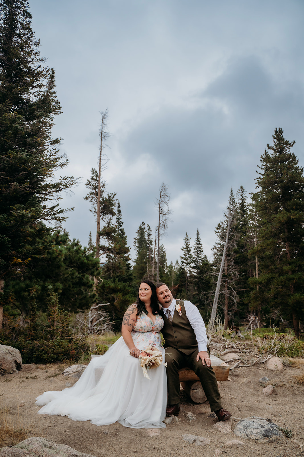 Bride and groom smile while seated together, relaxed and joyful in the quiet beauty of their intimate wedding in Colorado.