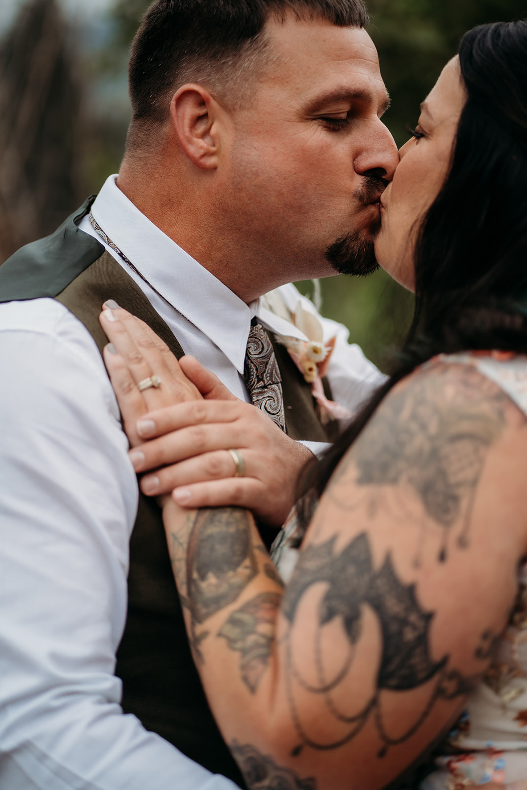 Intimate close-up of the couple sharing a kiss, the bride’s hand resting on the groom’s chest with wedding bands in focus.