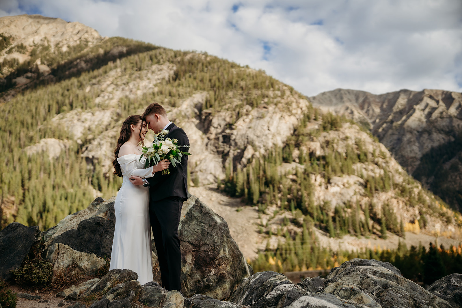 Nestled together among alpine peaks, the couple shares a quiet moment wrapped in each other’s arms.