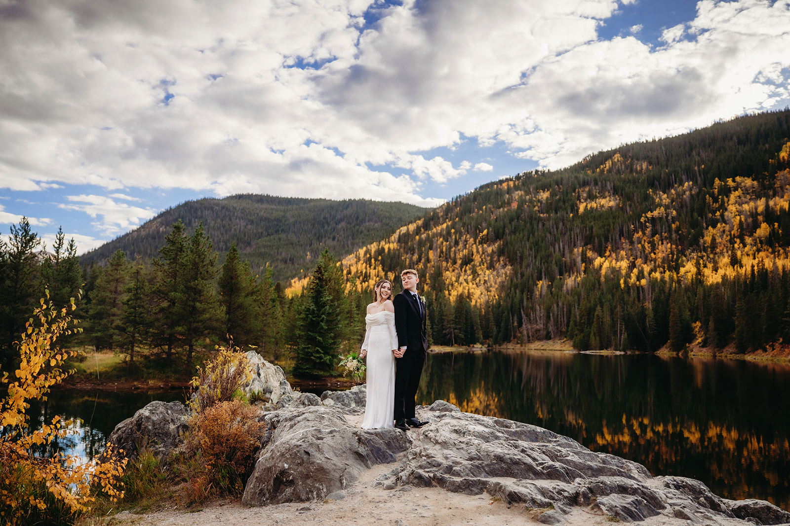 Holding hands atop a rocky outcrop, they stand still and strong, soaking in the peace of their choice to elope to Colorado.