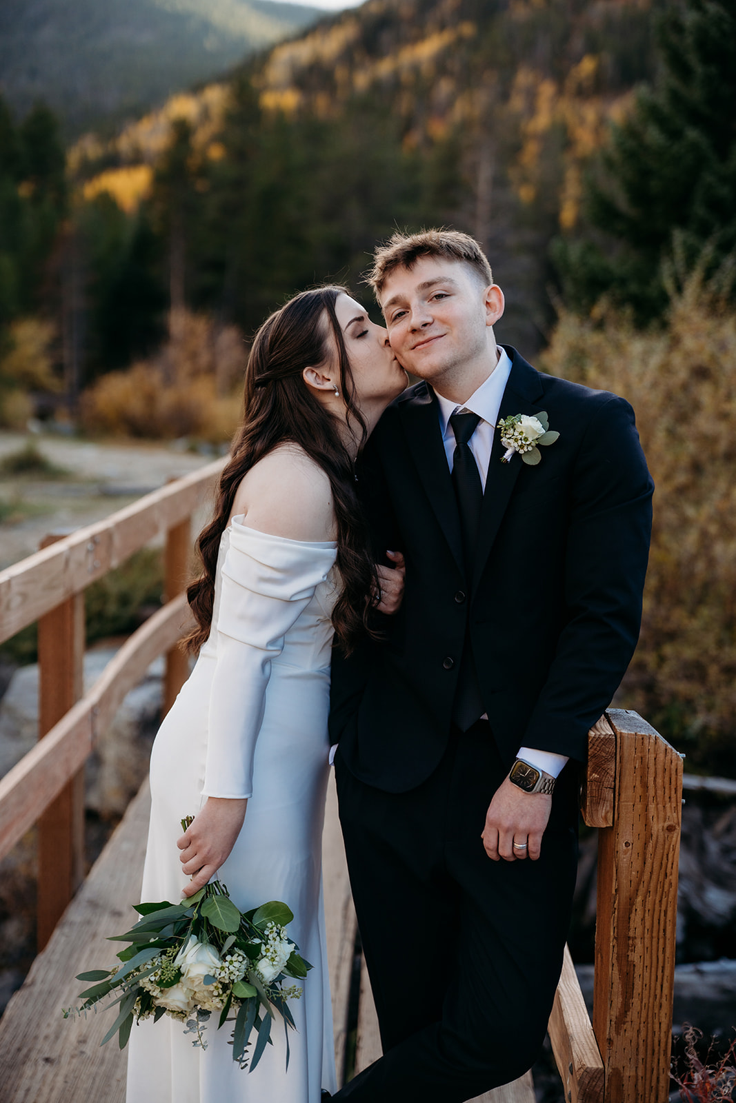 The bride leans into the groom’s forehead, smiling softly during their riverside vows.