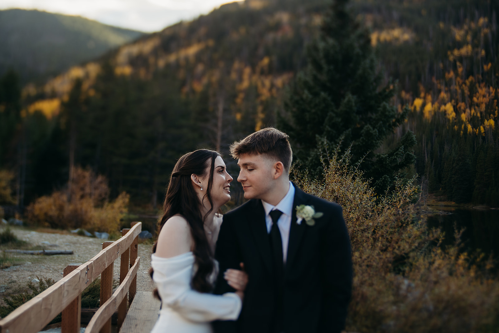 Bride with arms wrapped around groom's arm looking at him and smiling while they elope to Colorado