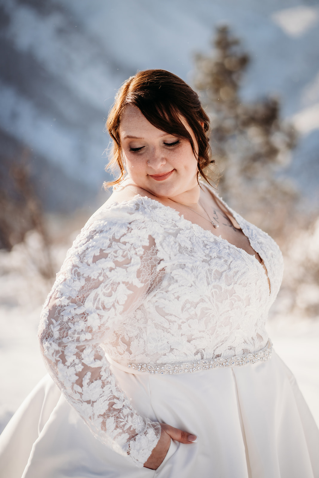 Bride in a long-sleeved white gown standing in fresh snow, a timeless and graceful take on winter wedding outfits.