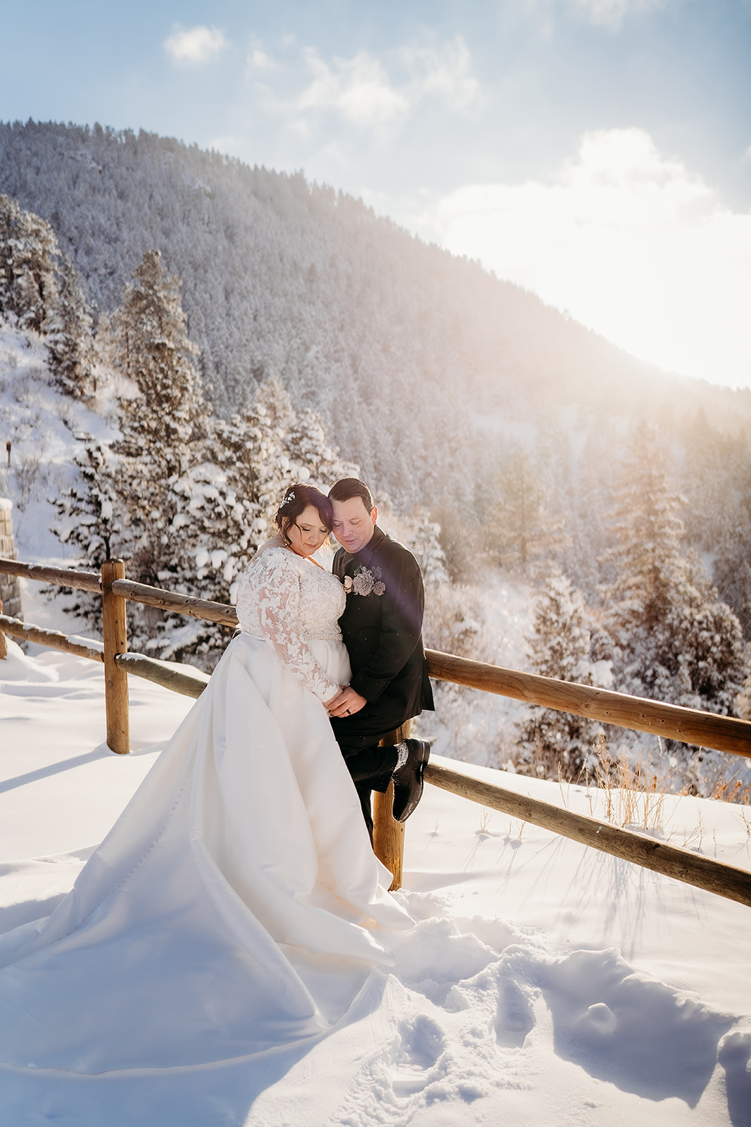 Bride and groom sharing a kiss on a snow-covered mountaintop with sweeping views and crisp winter light.