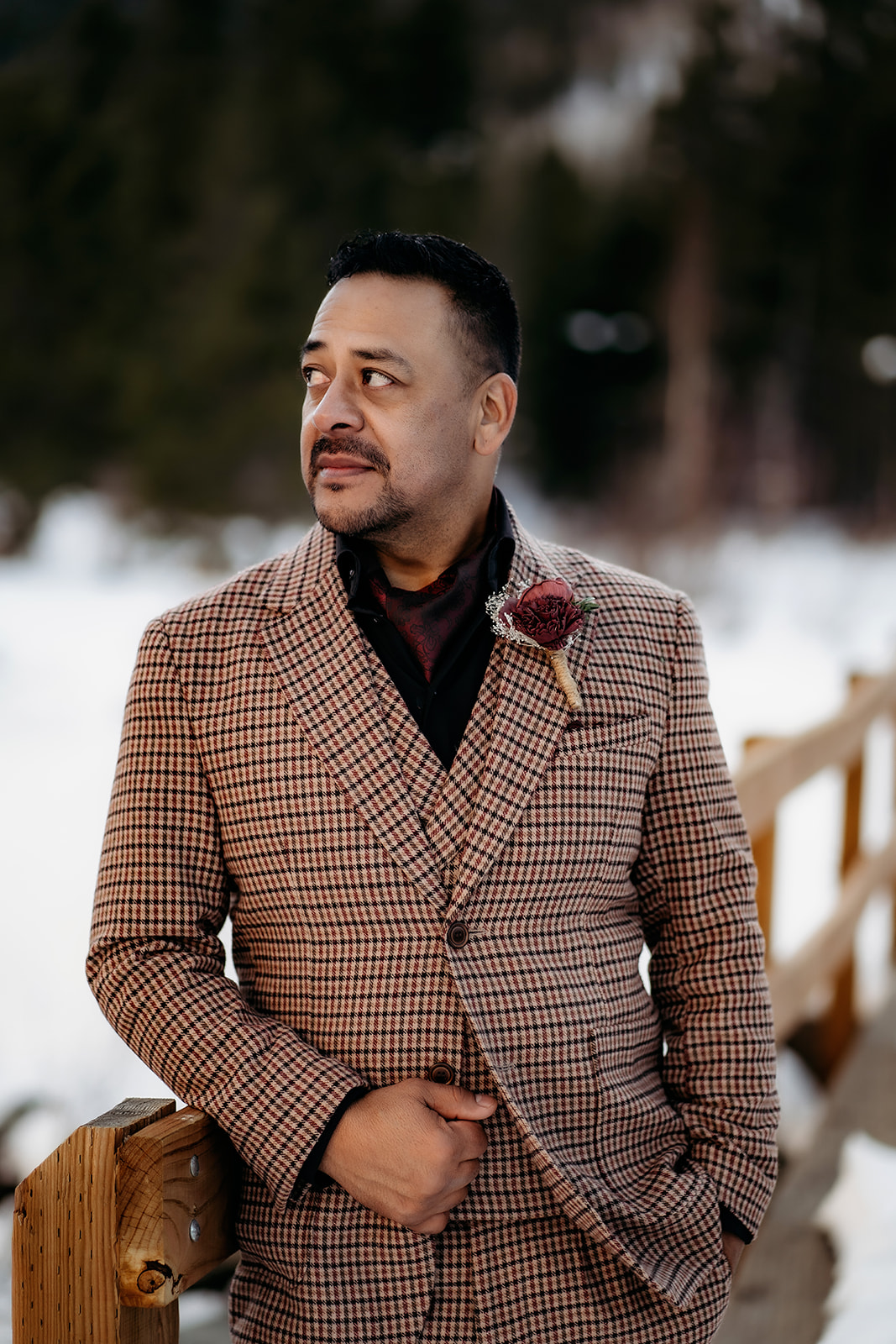 Groom in a checkered brown suit with boutonnière, styled perfectly for a mountain elopement in winter.