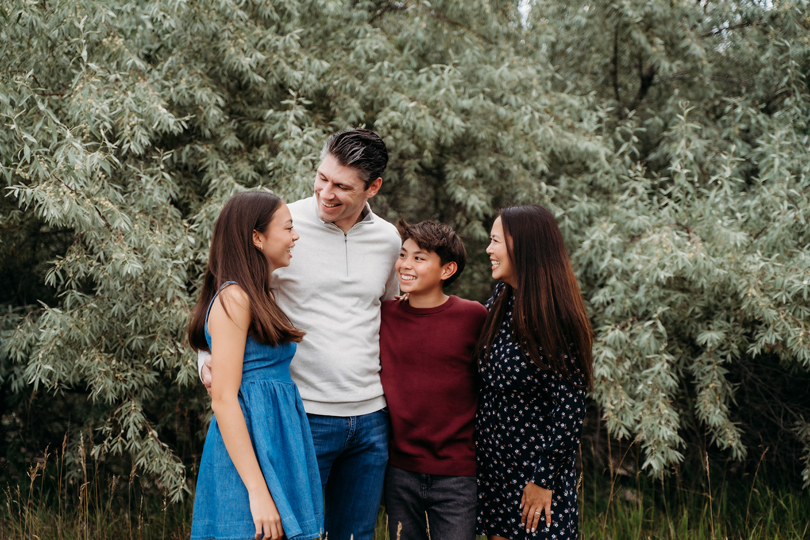 All four family members gather close, grinning at each other with nothing but love and laughter.