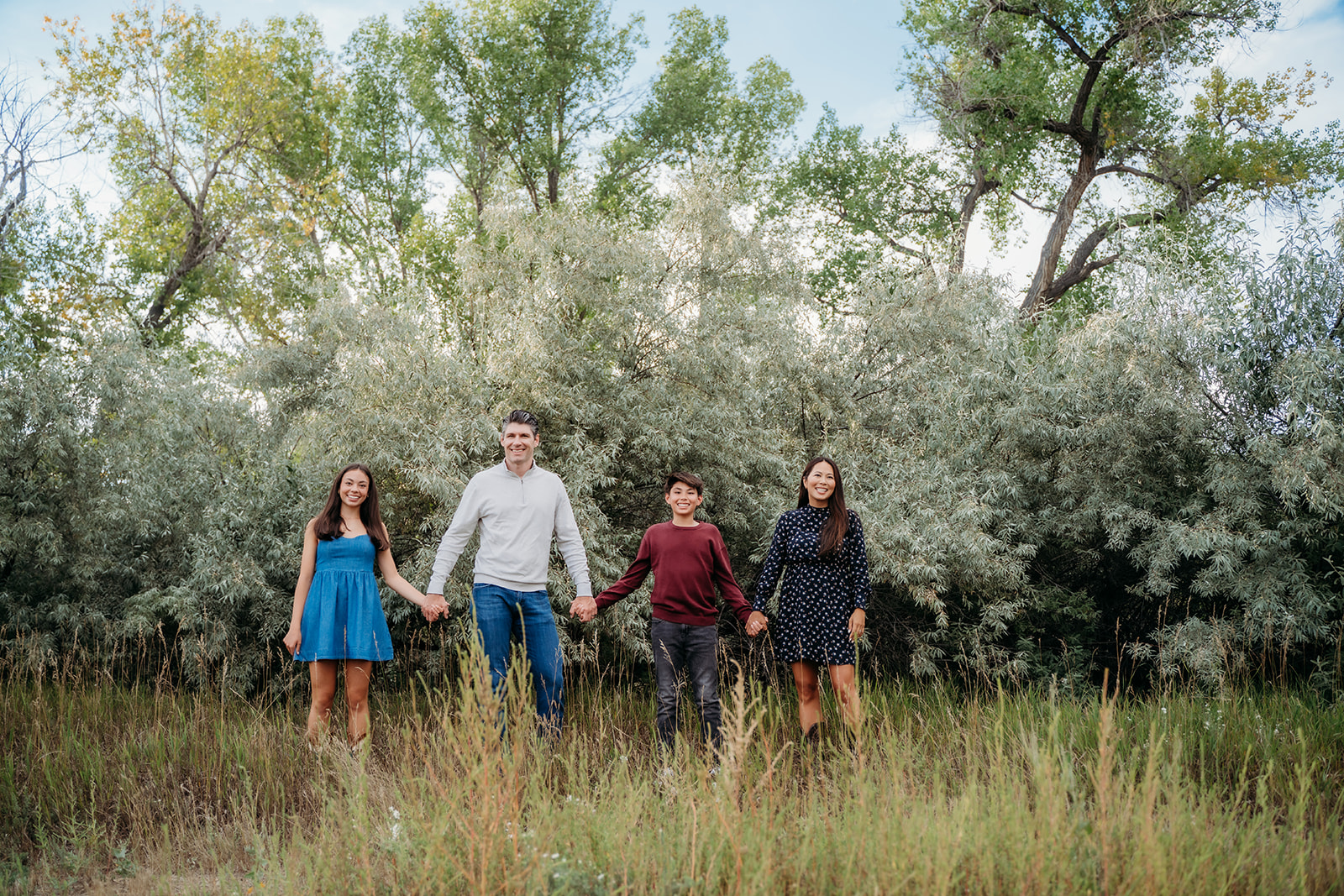 Everyone lined up, hand in hand, in front of silvery-green foliage—one of those timeless family outdoor pictures that feels like a memory already.