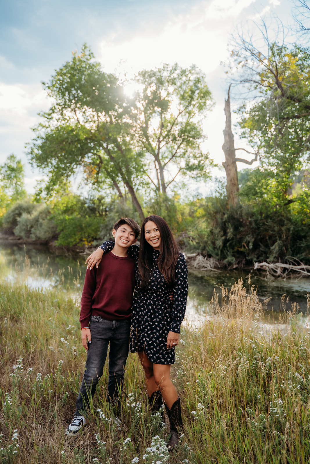 A proud mom poses with her son as soft morning light filters through the trees—family outdoor pictures at their most heartfelt.